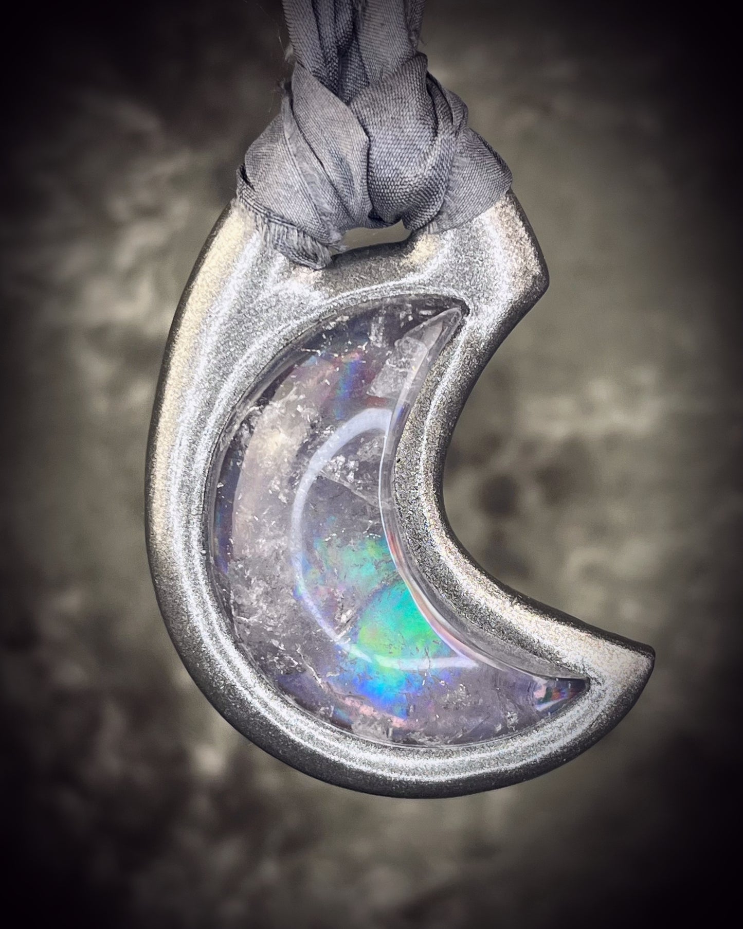 Black rainbow quartz crescent moon talisman on recycled silk with dark iridescent rainbow flashes, handcrafted by Become Spellbound.