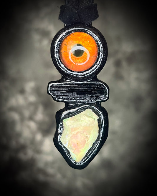 Black tourmaline and Libyan Desert Glass talisman with a man-made eye detail in a sculptural black-finish setting on black leather, handmade by Become Spellbound in Baltimore, Maryland.