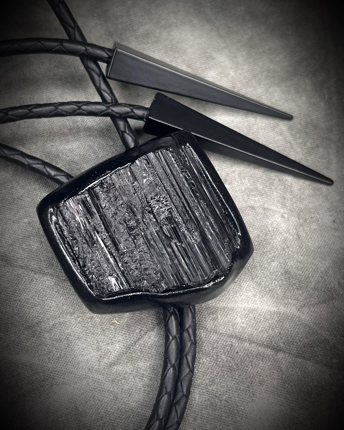 Black tourmaline crystal bolo tie with black spike tips on black leather, gothic statement jewelry for protection and grounding, handmade in Baltimore Maryland. 