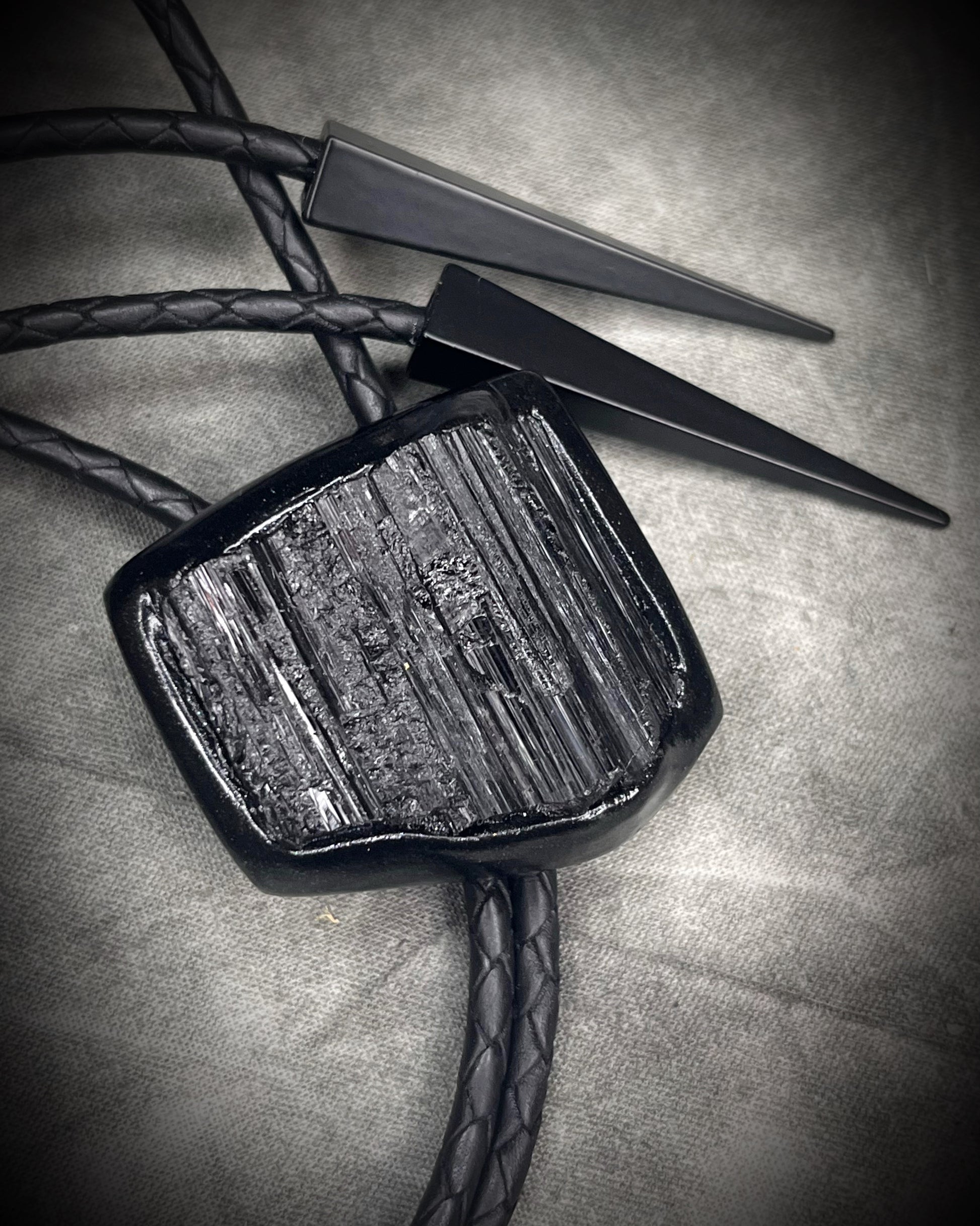 Black tourmaline crystal bolo tie with black spike tips on black leather, gothic statement jewelry for protection and grounding, handmade in Baltimore Maryland. 