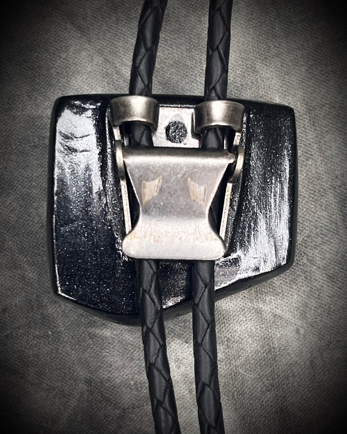 Black tourmaline crystal bolo tie with black spike tips on black leather, gothic statement jewelry for protection and grounding, handmade in Baltimore Maryland. Back clasp view. 