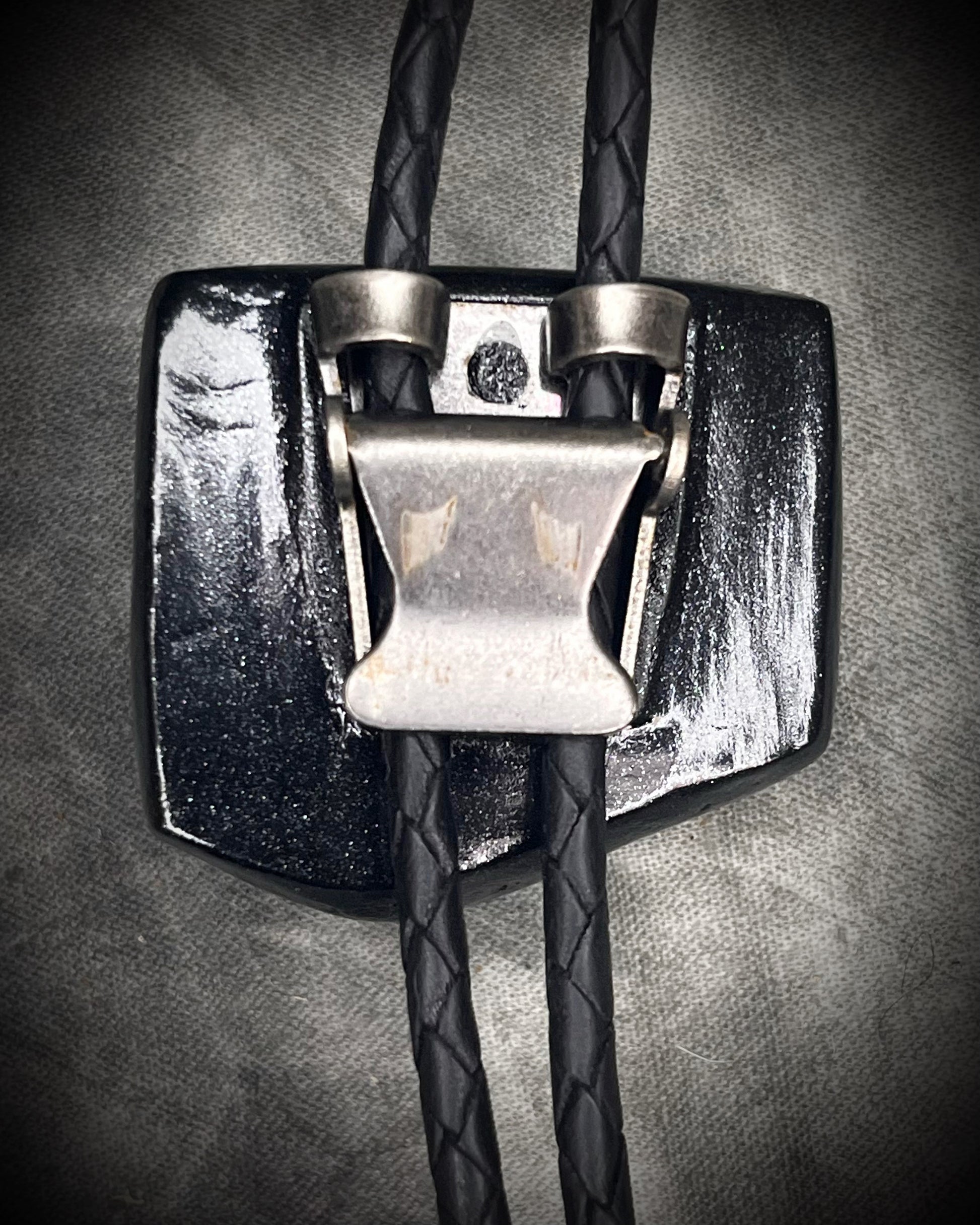 Black tourmaline crystal bolo tie with black spike tips on black leather, gothic statement jewelry for protection and grounding, handmade in Baltimore Maryland. Back clasp view. 