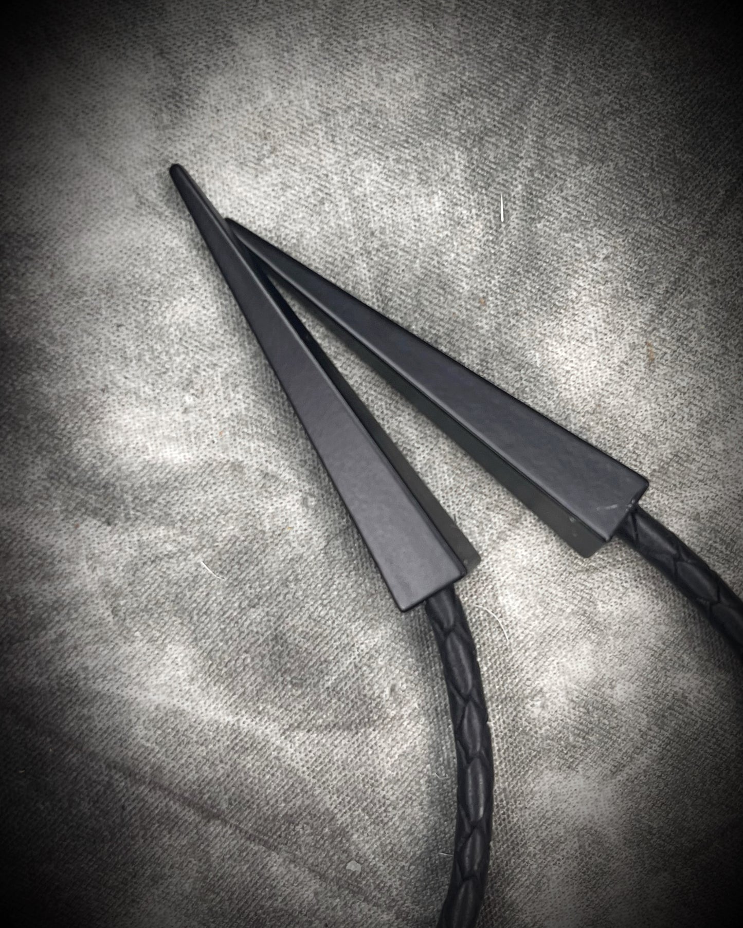 Black tourmaline crystal bolo tie with black spike tips on black leather, gothic statement jewelry for protection and grounding, handmade in Baltimore Maryland. Closeup of black bolo tips. 