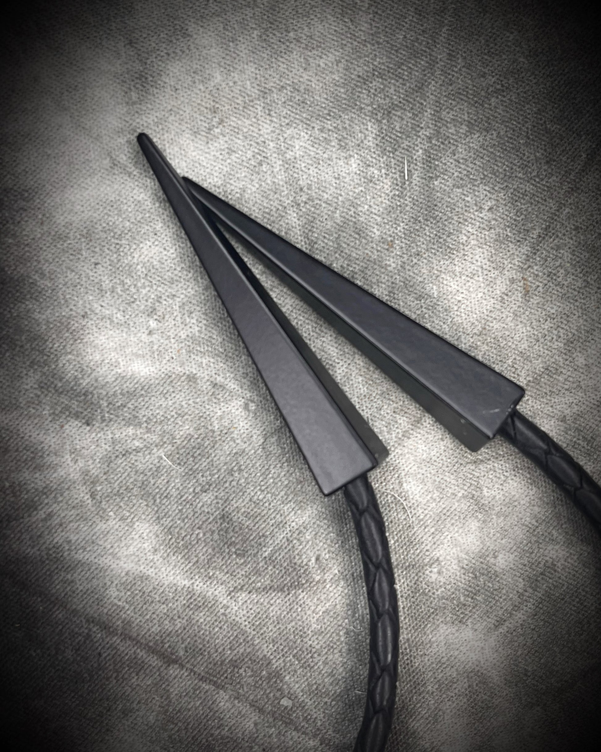 Black tourmaline crystal bolo tie with black spike tips on black leather, gothic statement jewelry for protection and grounding, handmade in Baltimore Maryland. Closeup of black bolo tips. 