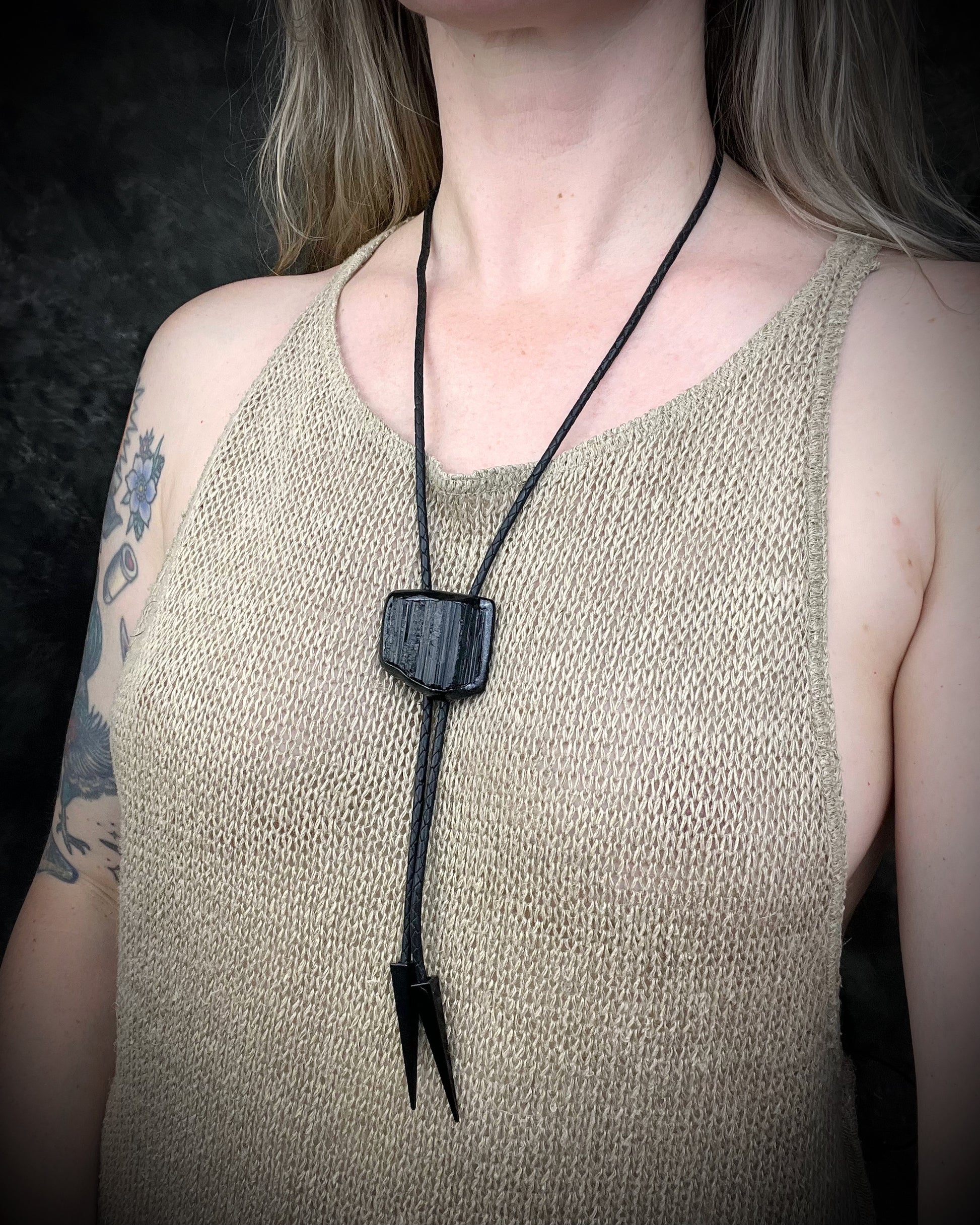 Black tourmaline crystal bolo tie with black spike tips on black leather, gothic statement jewelry for protection and grounding, handmade in Baltimore Maryland. Modeled here to show size. 