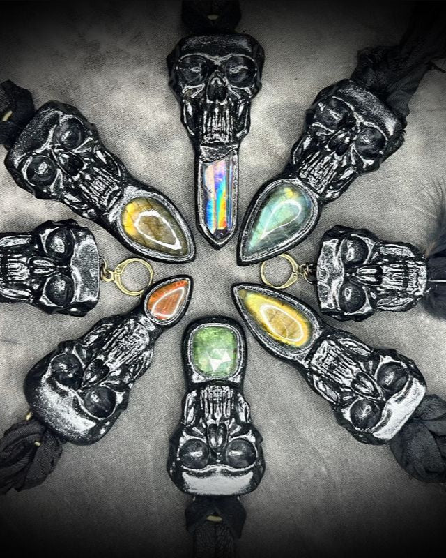 Necklace with skull pendants and colorful stones arranged in a circular pattern on a dark background.