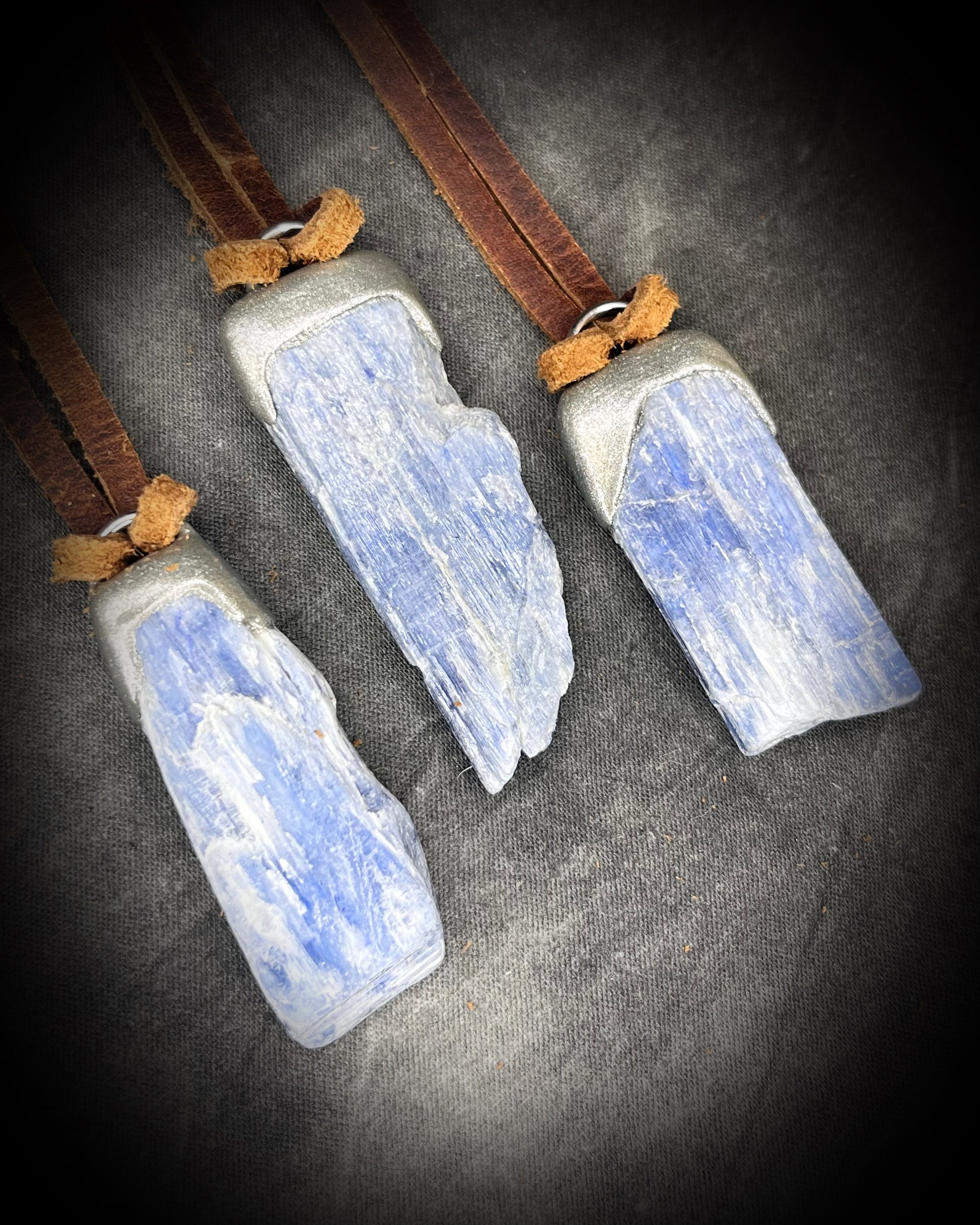 Blue Kyanite crystal pendant in silver finish, hung from organic brown leather for earthy elegance. Raw gemstone talismans for truth, communication and wisdom make perfect holiday gifts!
