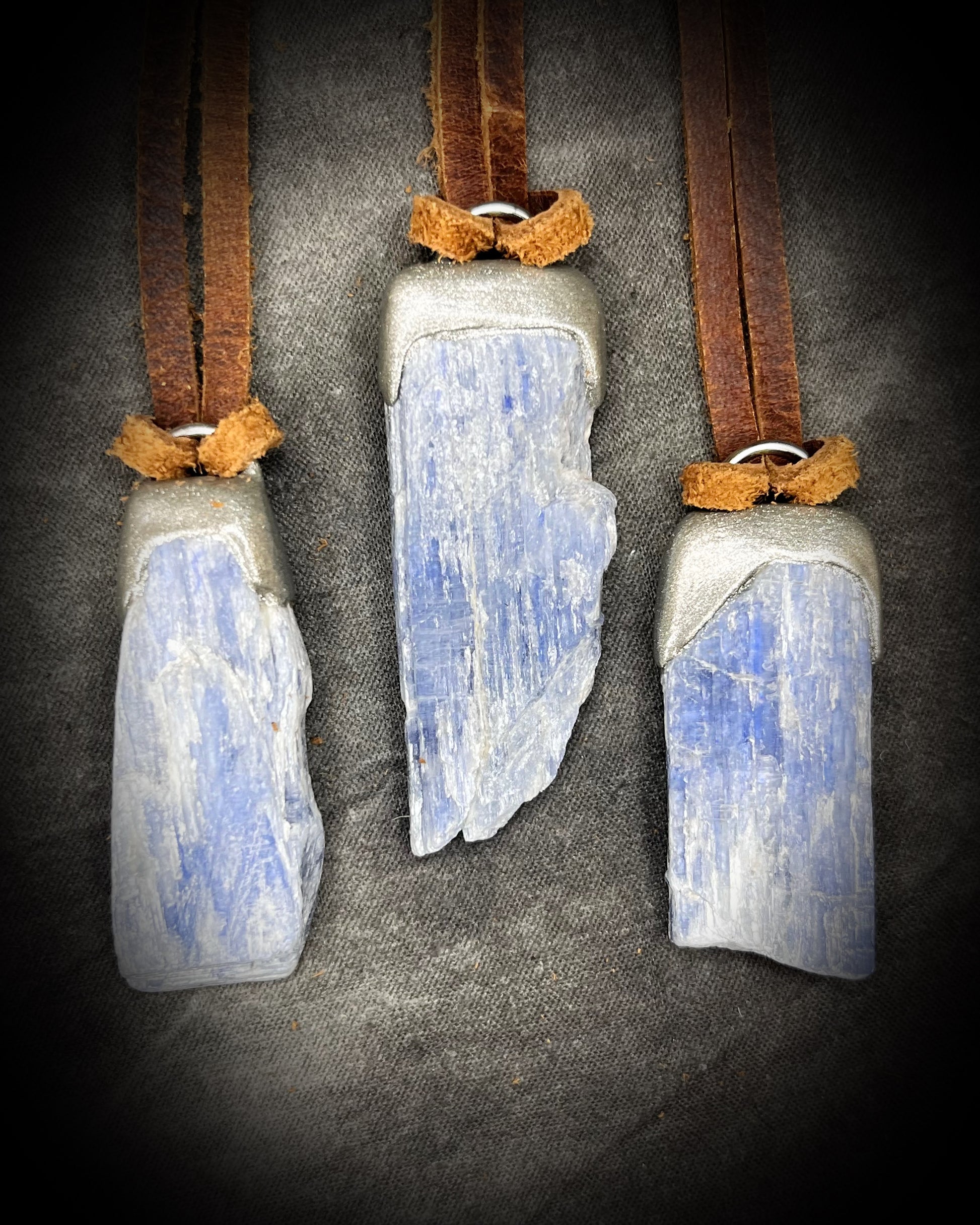 Blue Kyanite crystal pendant in silver finish, hung from organic brown leather for earthy elegance. Raw gemstone talismans for truth, communication and wisdom make perfect holiday gifts!