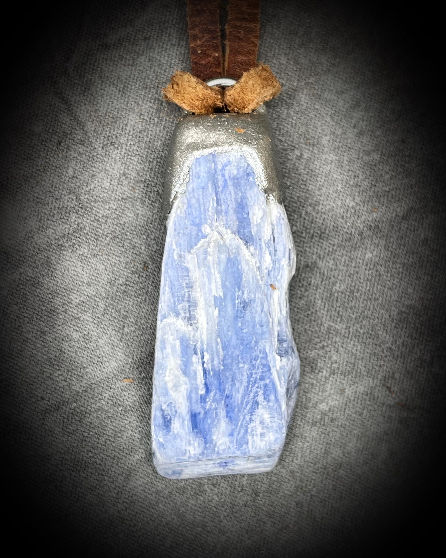 Blue Kyanite crystal pendant in silver finish, hung from organic brown leather for earthy elegance. Raw gemstone talismans for truth, communication and wisdom make perfect holiday gifts!