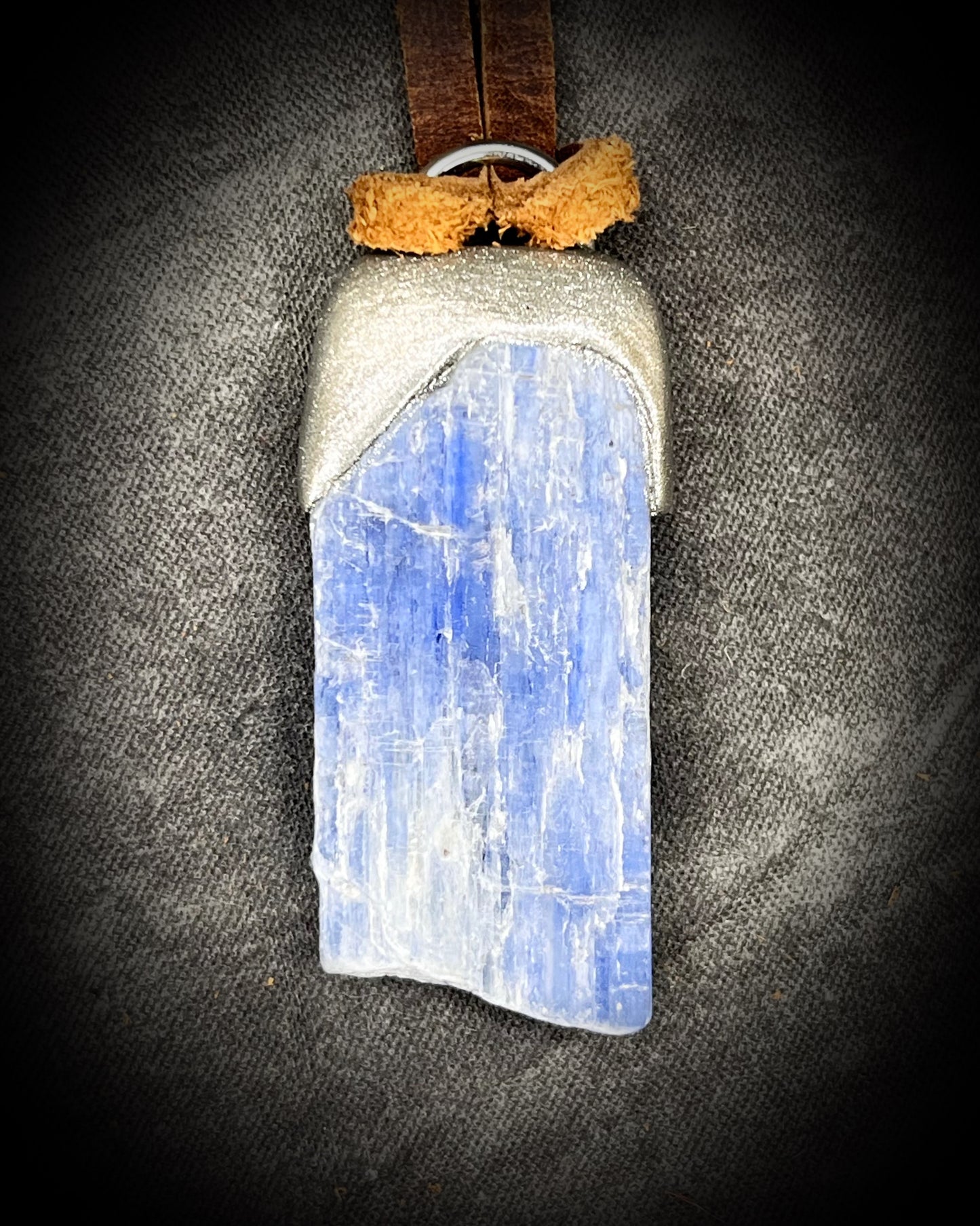 Blue Kyanite crystal pendant in silver finish, hung from organic brown leather for earthy elegance. Raw gemstone talismans for truth, communication and wisdom make perfect holiday gifts!
