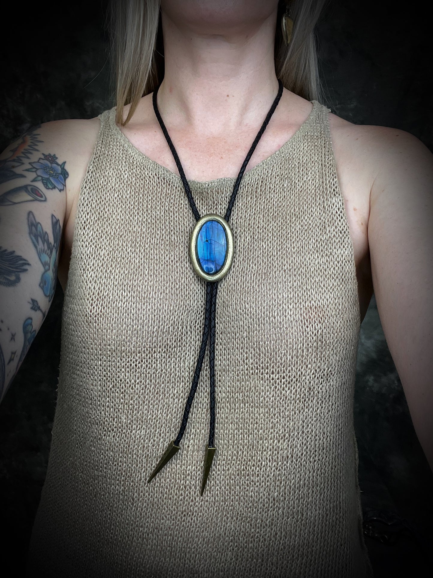 Blue flash labradorite bolo tie with black leather cord, gold finish, and antique gold spike bolo tips. Handmade by Become Spellbound.