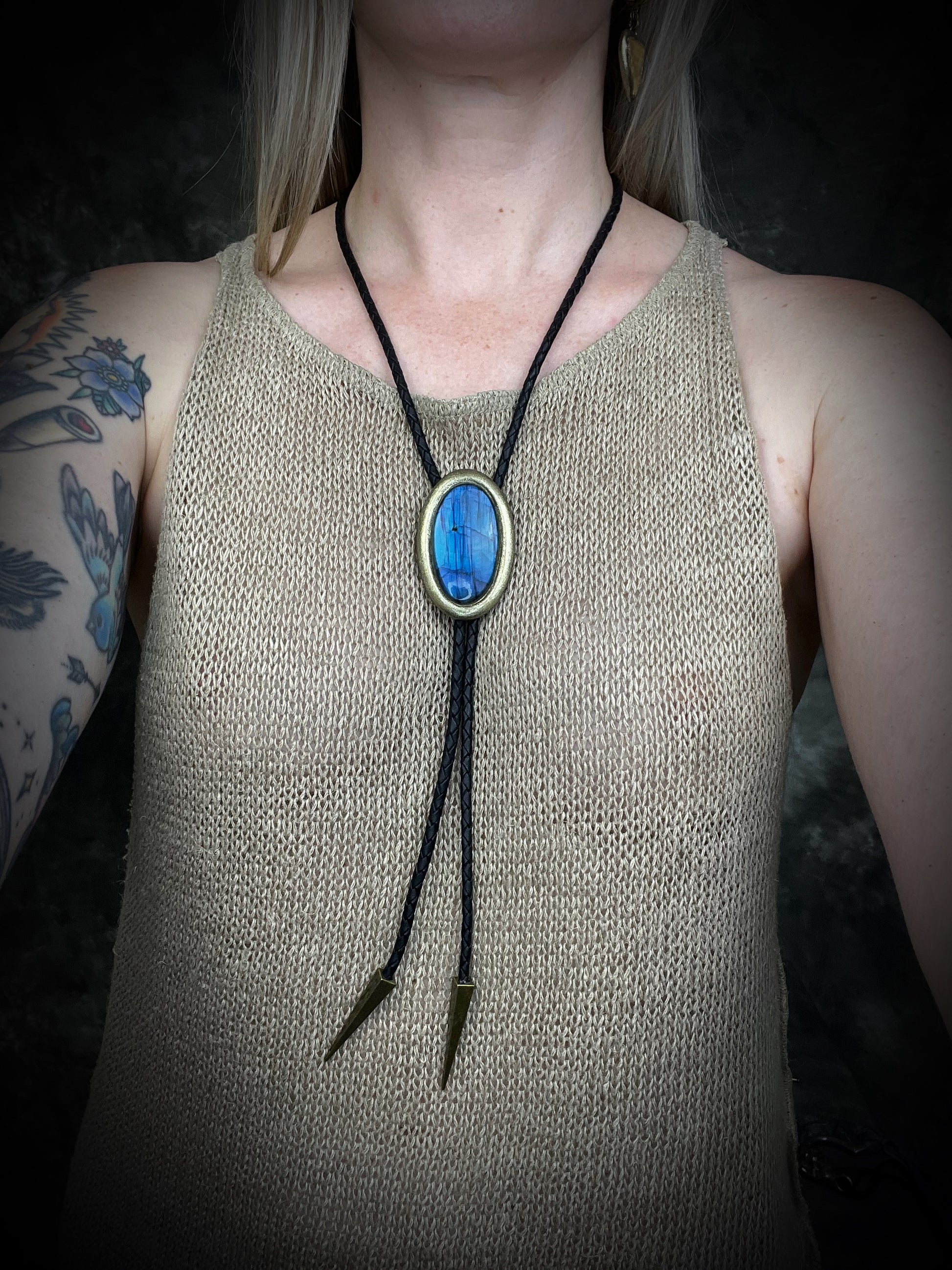 Blue flash labradorite bolo tie with black leather cord, gold finish, and antique gold spike bolo tips. Handmade by Become Spellbound.
