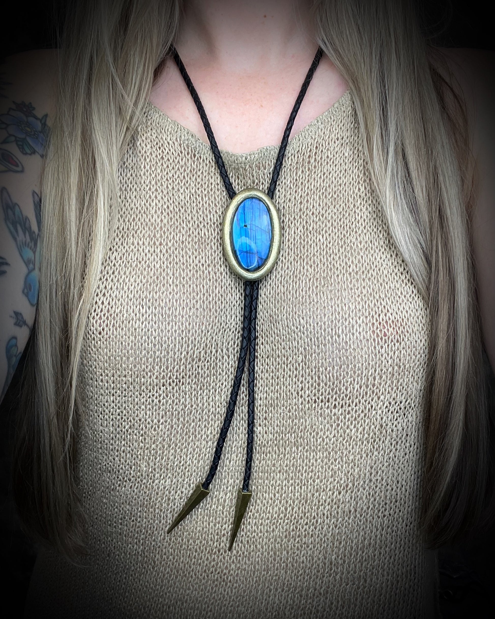 Blue flash labradorite bolo tie with black leather cord, gold finish, and antique gold spike bolo tips. Handmade by Become Spellbound.