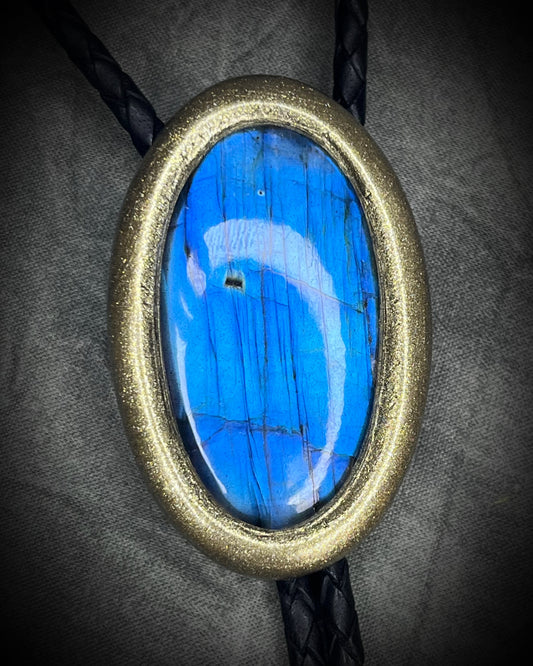 Blue flash labradorite bolo tie with black leather cord, gold finish, and antique gold spike bolo tips. Handmade by Become Spellbound.
