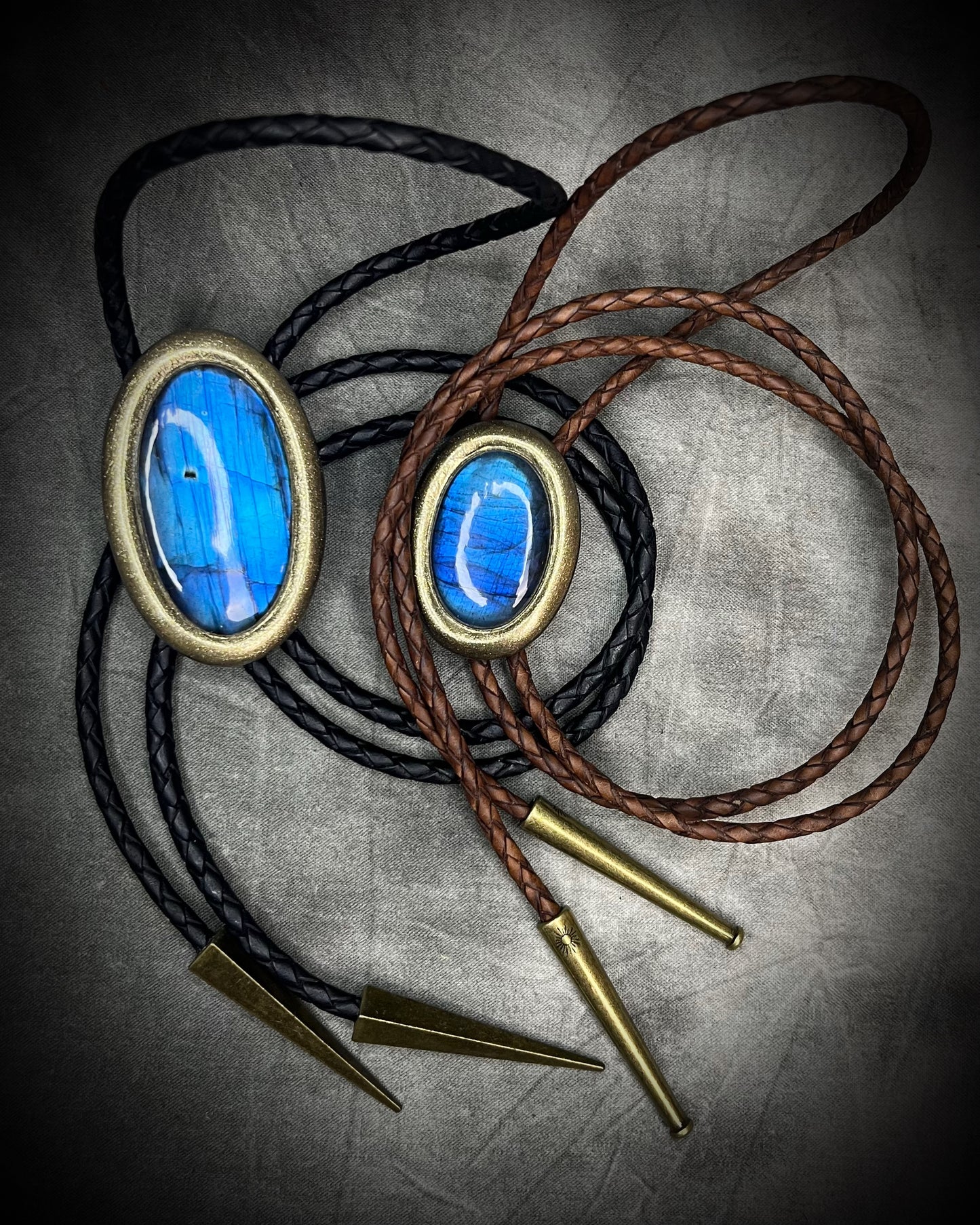 Blue flash labradorite bolo tie with black leather cord, gold finish, and antique gold spike bolo tips. Handmade by Become Spellbound.