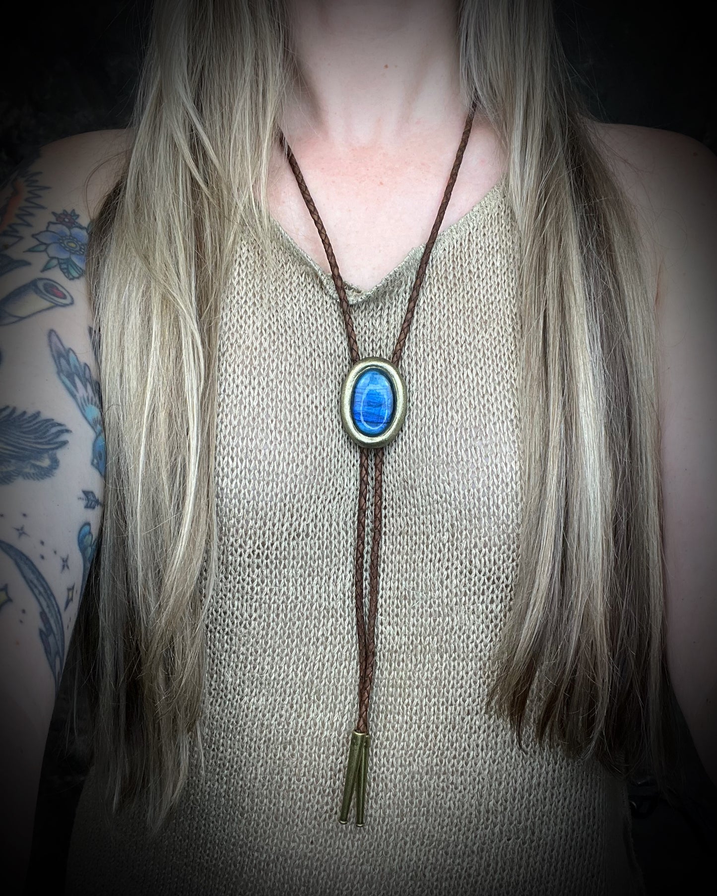 Blue flash labradorite bolo tie with brown leather cord, gold finish, and decorative sunburst bolo tips. Handmade by Become Spellbound.
