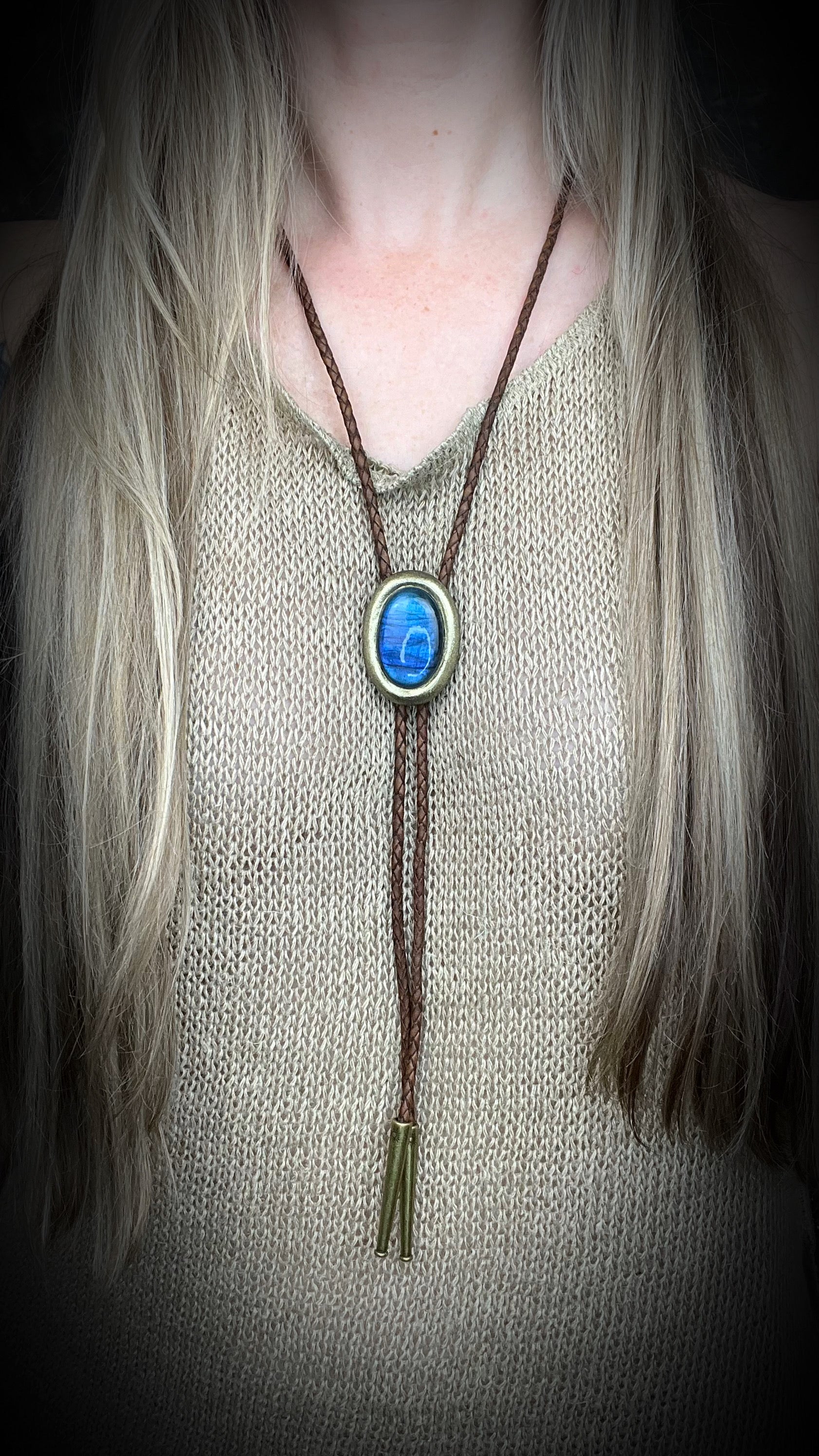 Blue flash labradorite bolo tie with brown leather cord, gold finish, and decorative sunburst bolo tips. Handmade by Become Spellbound.
