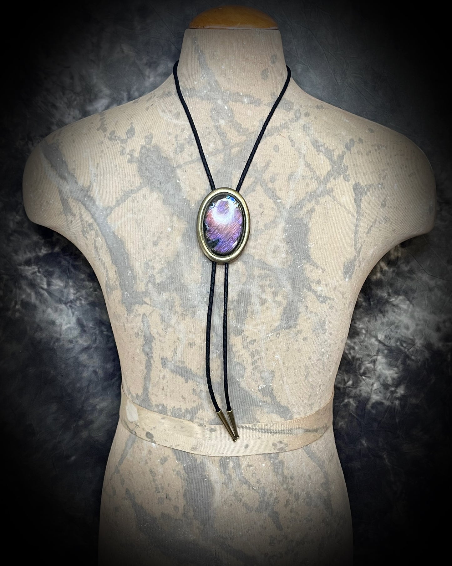 Bolo Tie Necklace with a colorful stone pendant on a male model and gold brass tips.
