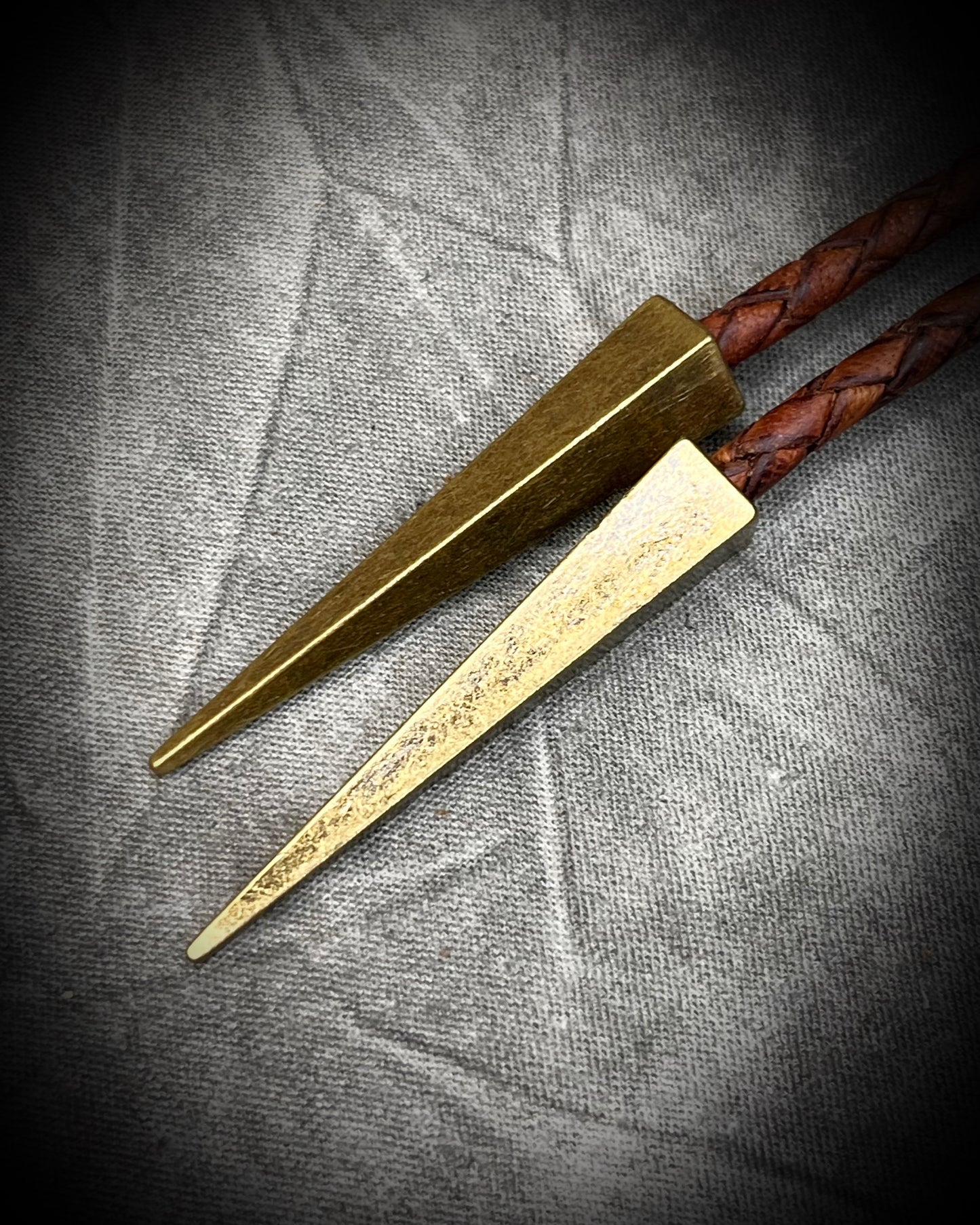 Bolo tips closeup for Raw Dioptase teal colored gemstone Bolo tie set in a gold finish and mounted on earthy brown leather. A talisman for heart chakra healing, crystal jewelry for him. Western 2026 jewelry trend bolo. 