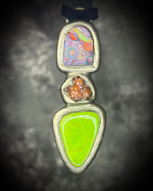 Cadillac Ranch Fordite talisman with a hand-cut Fordite cabochon, spessartine garnet, and lime green natural turquoise in a sculptural setting on black leather, handmade by Become Spellbound in Baltimore, Maryland.