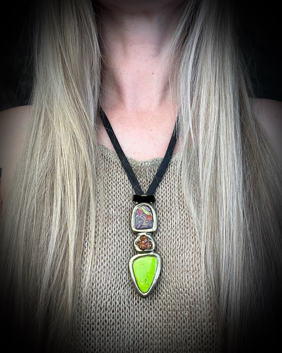 Cadillac Ranch Fordite talisman with a hand-cut Fordite cabochon, spessartine garnet, and lime green natural turquoise in a sculptural setting on black leather, handmade by Become Spellbound in Baltimore, Maryland.