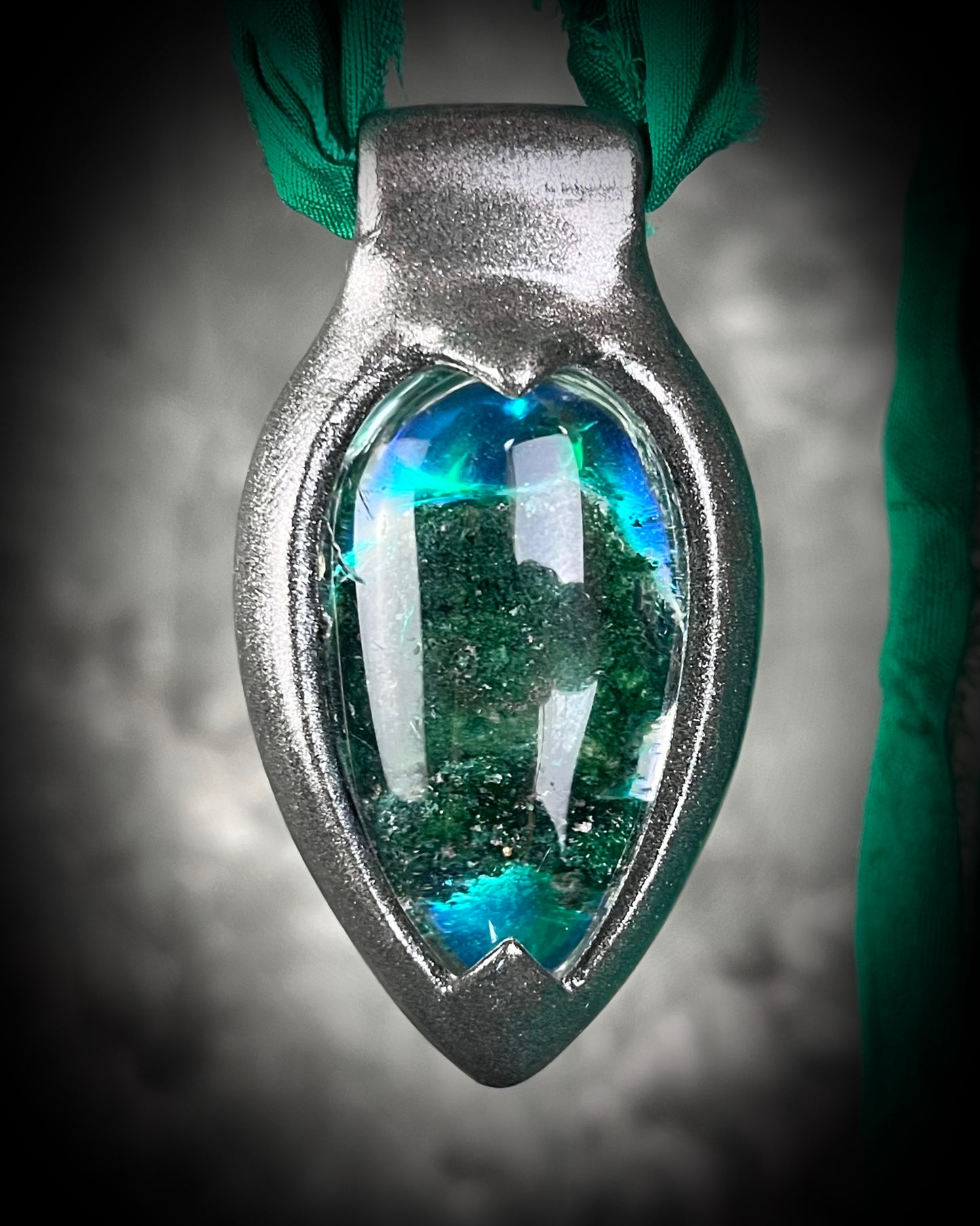 Chlorite Included Quartz necklace in a dark silver gunmetal finish on emerald green recycled silk, glowing with natural green mosslike crystal inclusions.