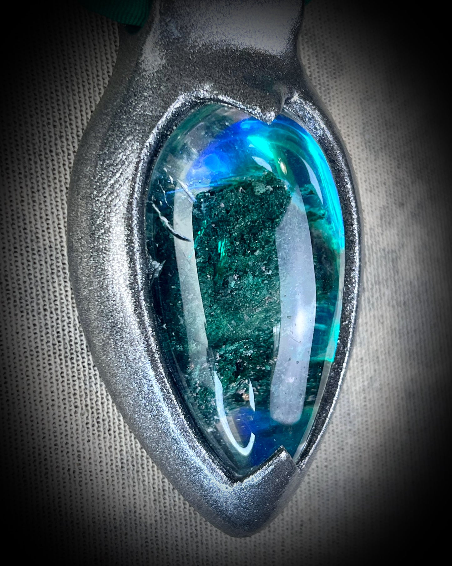 Chlorite Included Quartz necklace in a dark silver gunmetal finish on emerald green recycled silk, glowing with natural green mosslike crystal inclusions.