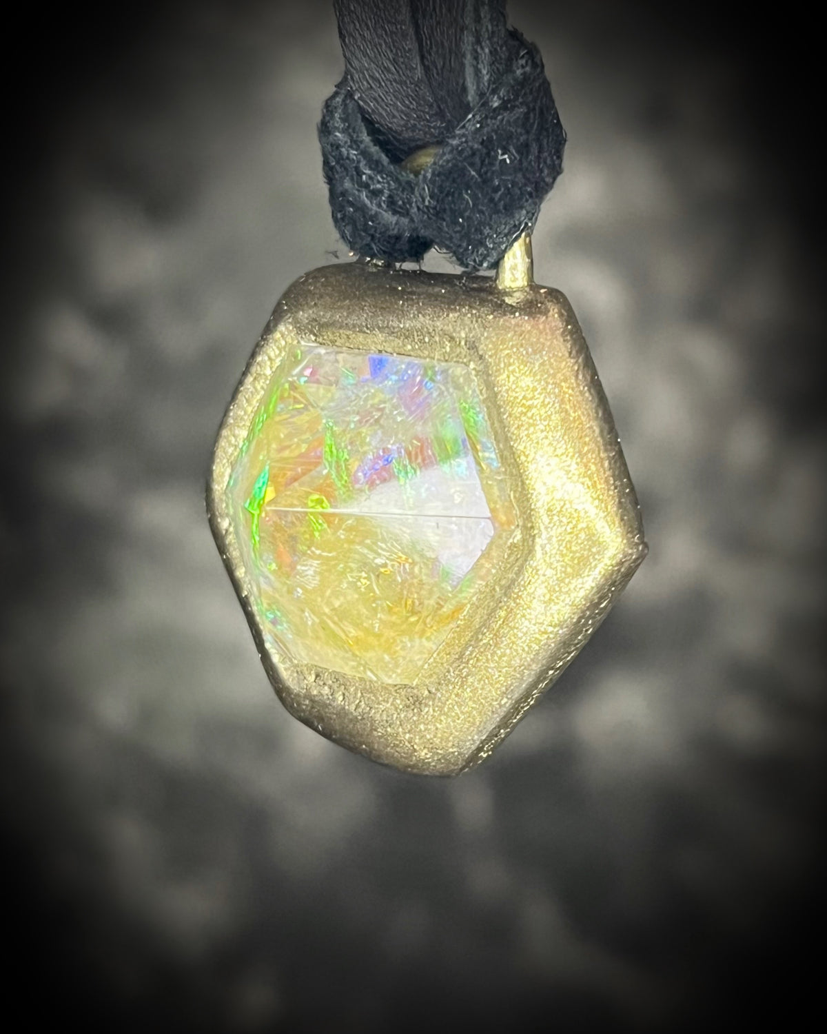 Citrine quartz pyramid crystal with a mystical green glow in a sculptural gold-finish talisman setting on black leather, handmade by Become Spellbound in Baltimore, Maryland.