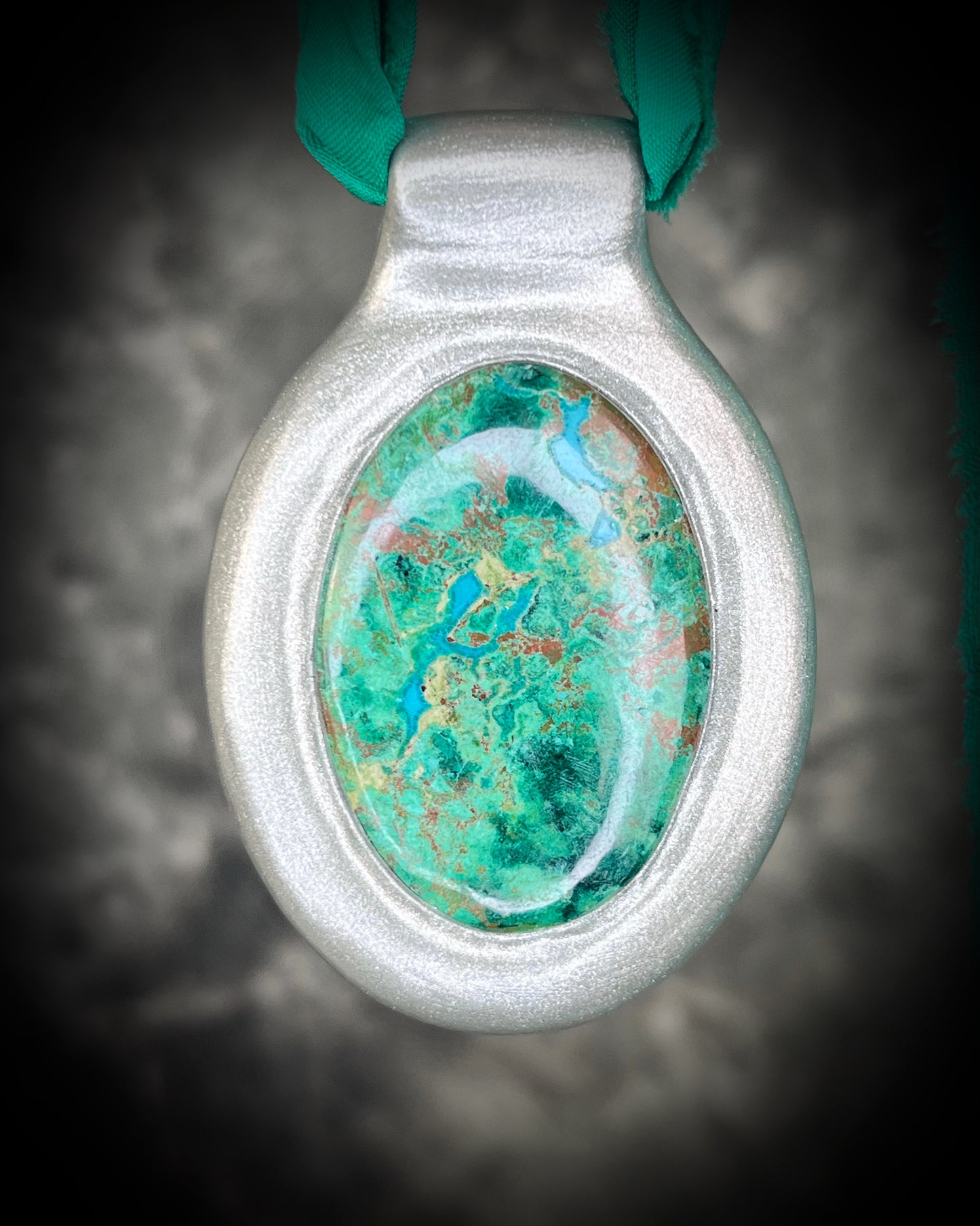 Oval Chrysocolla gemstone pendant in silver finish on emerald green recycled silk cord. Close-up of Chrysocolla crystal showing natural turquoise-green matrix