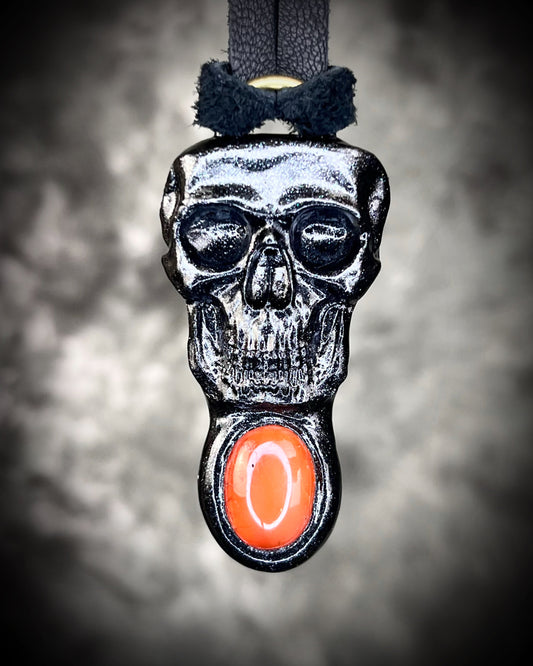 Close-up of black skull and orange carnelian crystal talisman on black leather cord, gothic and mystical jewelry for fall, cosplay, renaissance festival, handcrafted statement necklace.