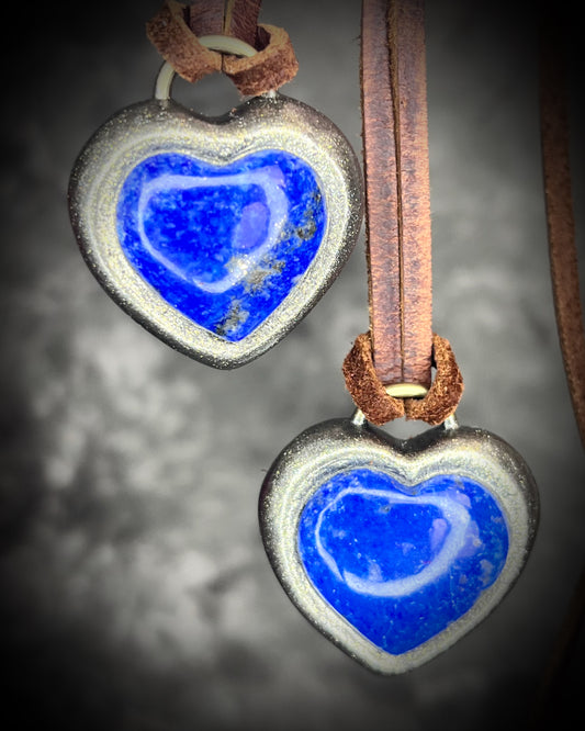 Close-up of two lapis lazuli heart pendants showing gold details and organic texture, artisan necklace for spiritual connection.