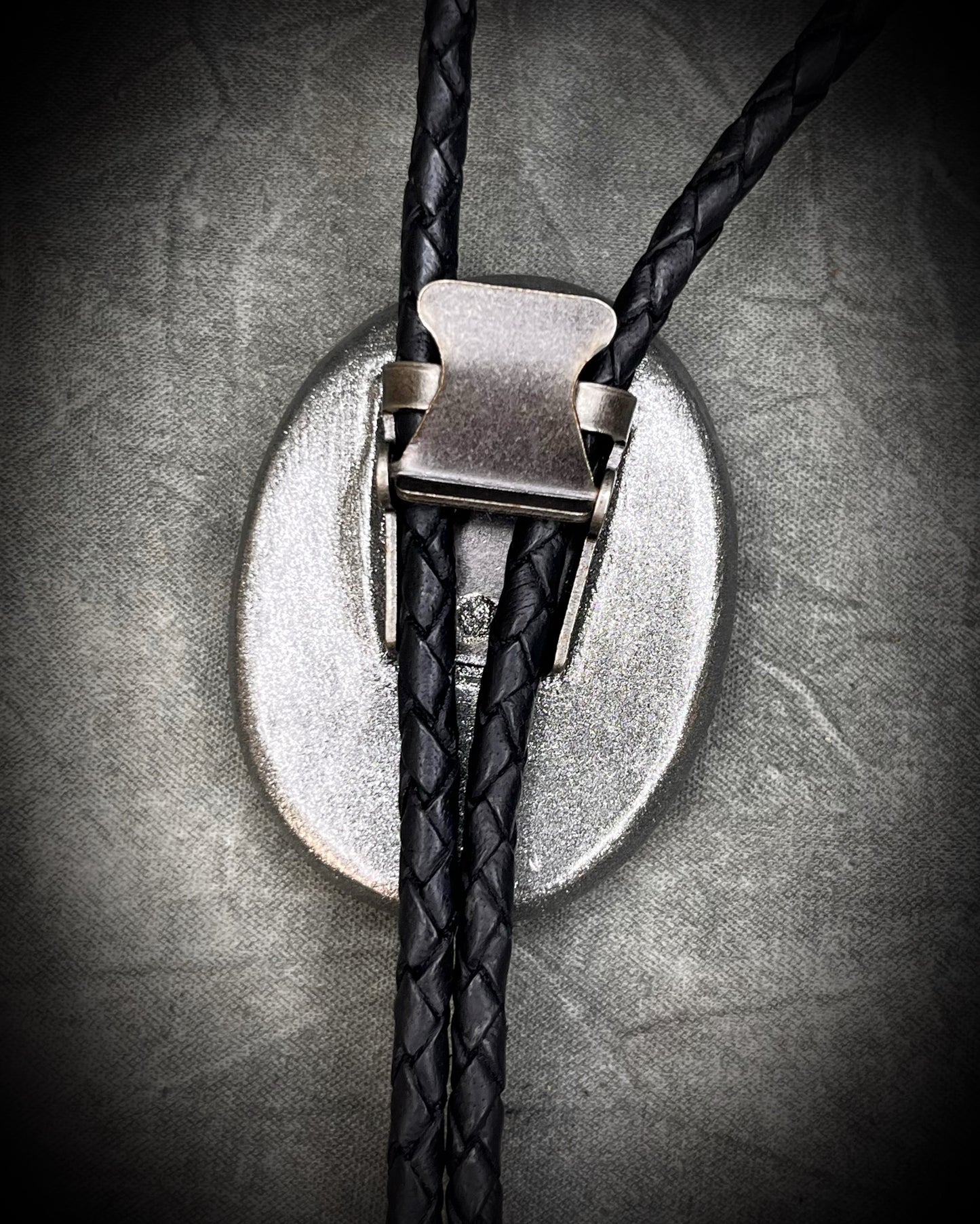 Closeup of back clasp for Fordite manmade colorful swirling gemstone Bolo tie set in a gunmetal silver finish and mounted on soft black bolo leather. A talisman for the modern man, crystal jewelry for him. Western 2026 jewelry trend bolo. 