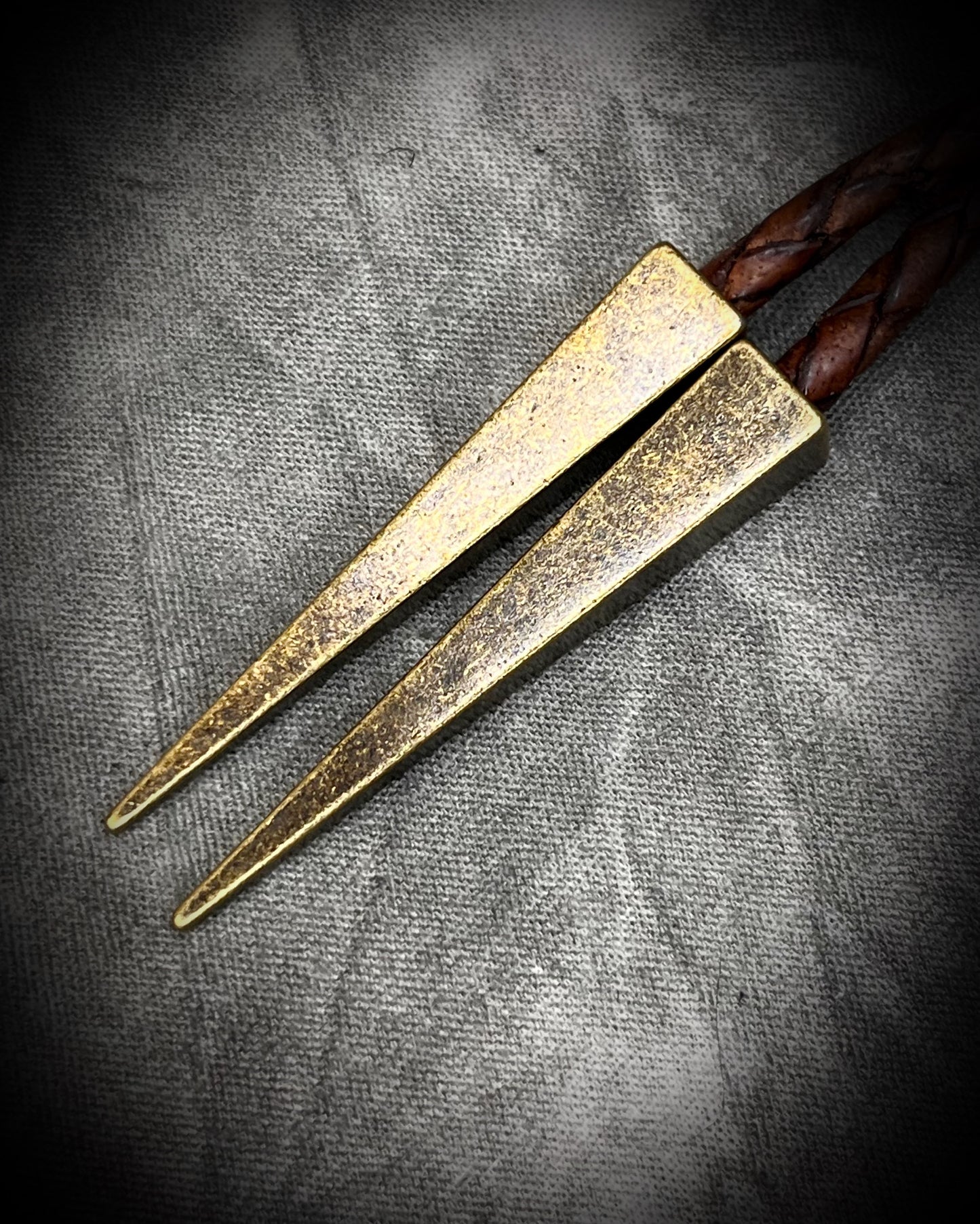 Closeup of brass bolo spike tips. Raw Pyrite gemstone Bolo tie set in an invisible finish and mounted on earthy brown leather. A talisman for ambition, success, and manifestation. Western 2026 jewelry trend bolo. 