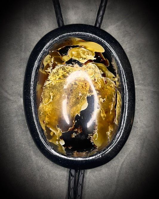 Closeup of swirling Indonesian Amber XL black on black bolo tie with black spike tips. Western Gothic fantasy jewelry for 2026 fashion trends and gift for him or her. 