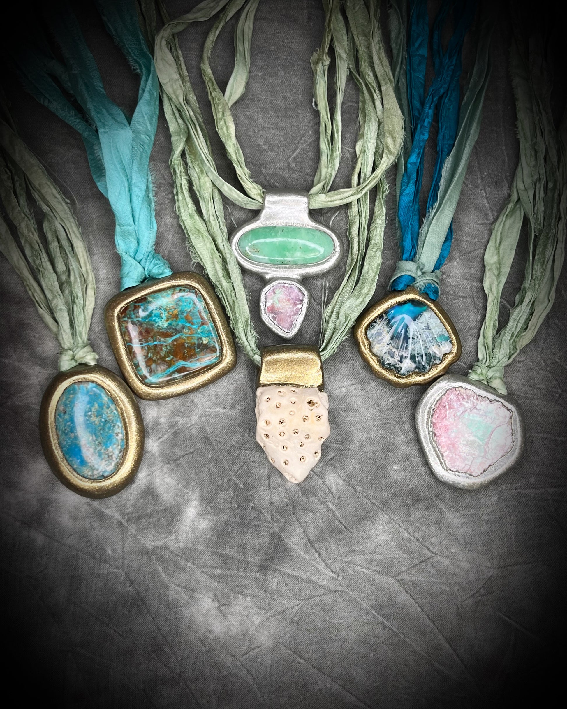 Collection of necklaces with various ocean inspired crystal and fossil pendants all hung from shades of aqua and sea green recycled silk. Summer beach jewelry gift for her. 