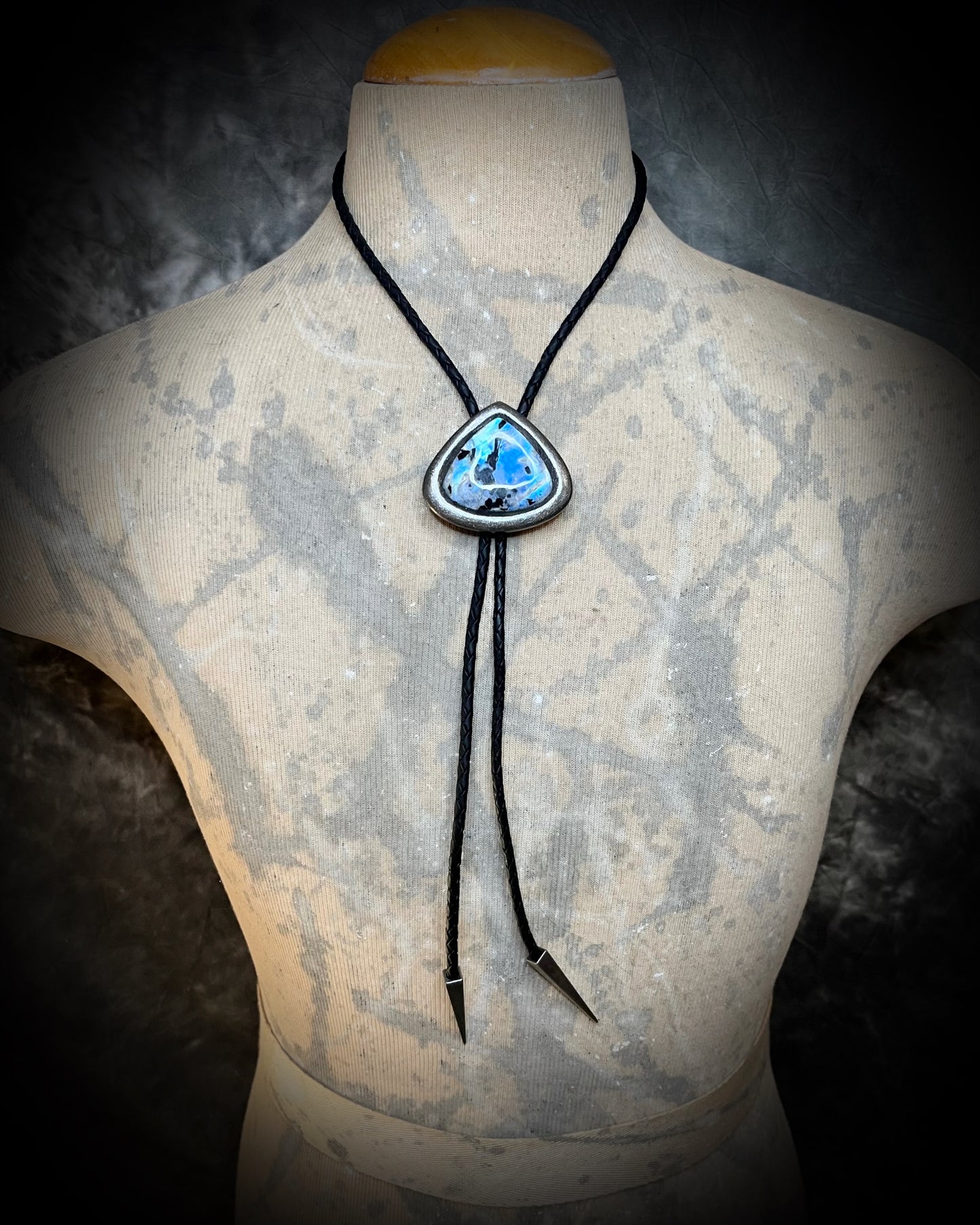 Crystal bolo tie styled as statement necklace on neutral male model. Rainbow moonstone teardrop shaped gunmetal silver finish bolo tie for him or her. 