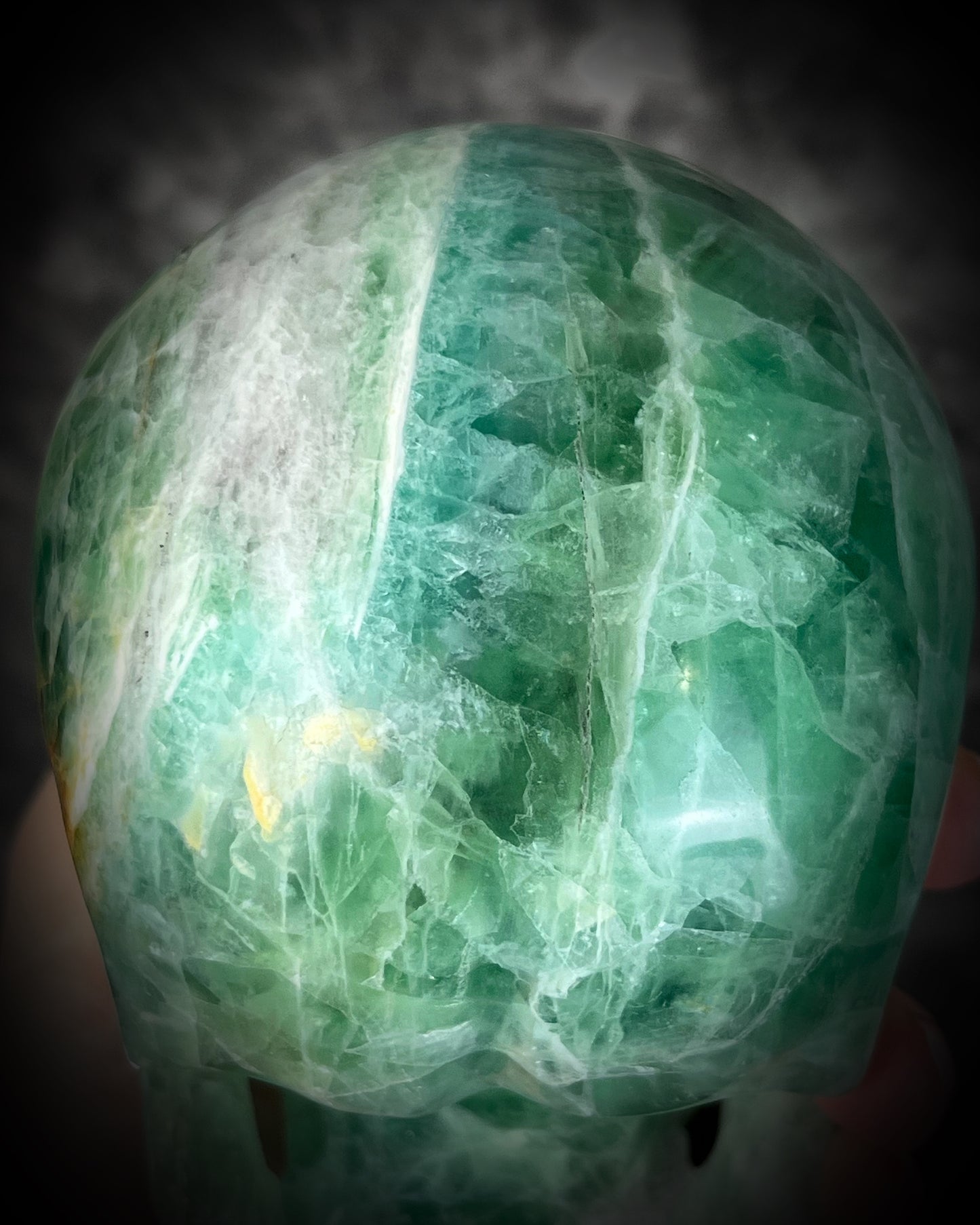 Detail shot of Large 5-inch green fluorite crystal skull with layered green bands and polished carved features.
