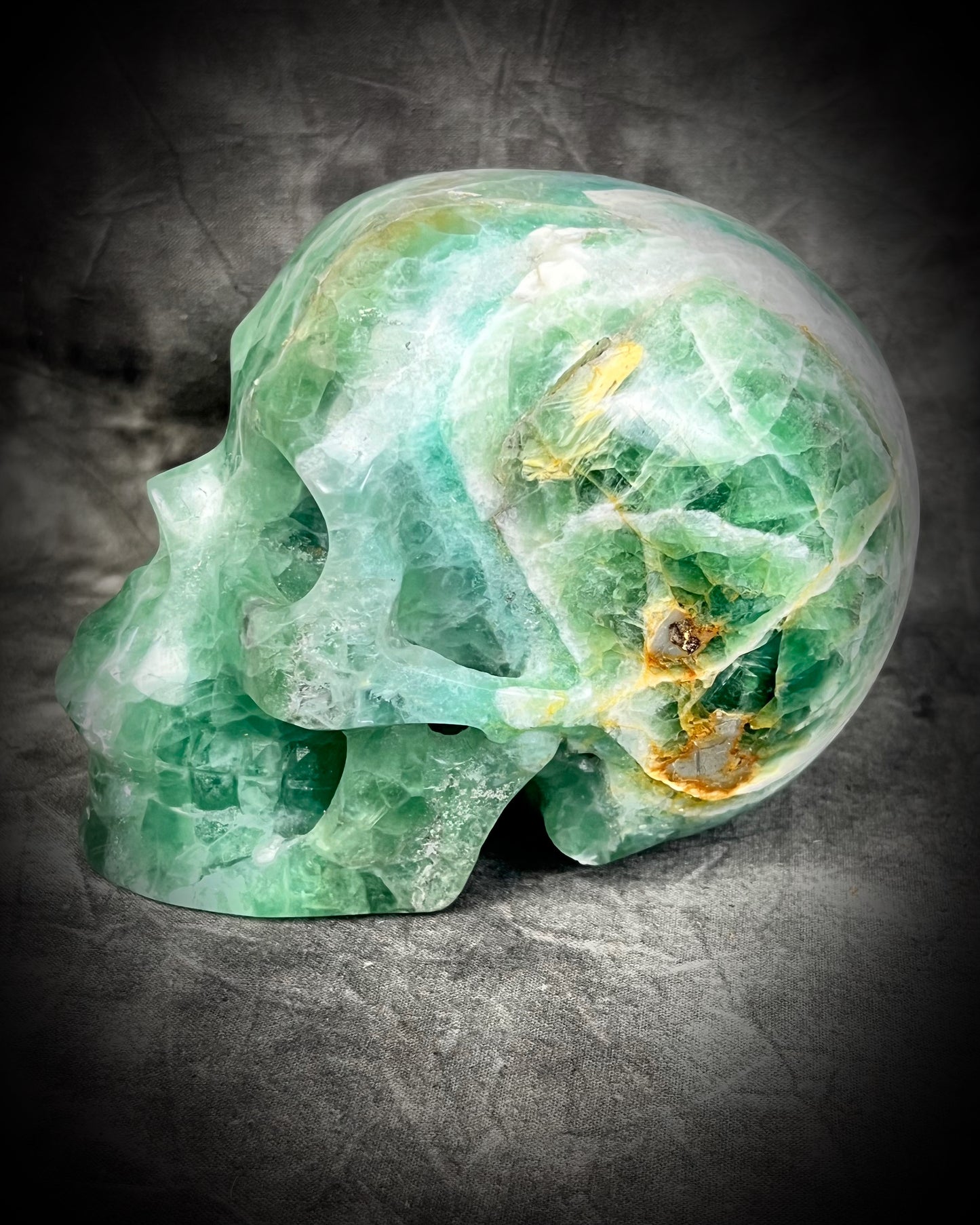 Detail shot of Large 5-inch green fluorite crystal skull with layered green bands and polished carved features.