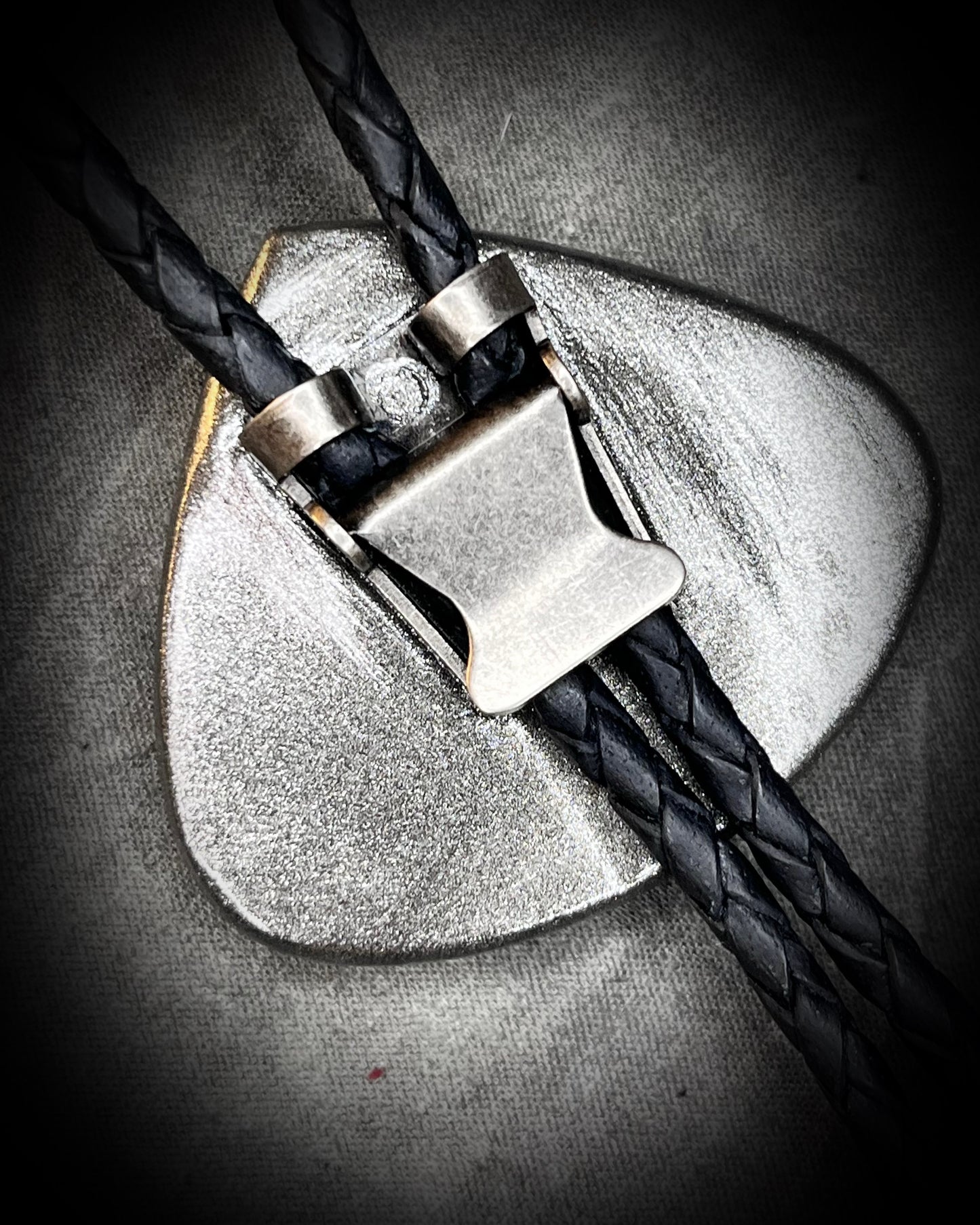 Detail view showing texture of leather cord and silver slide for moonstone bolo tie.