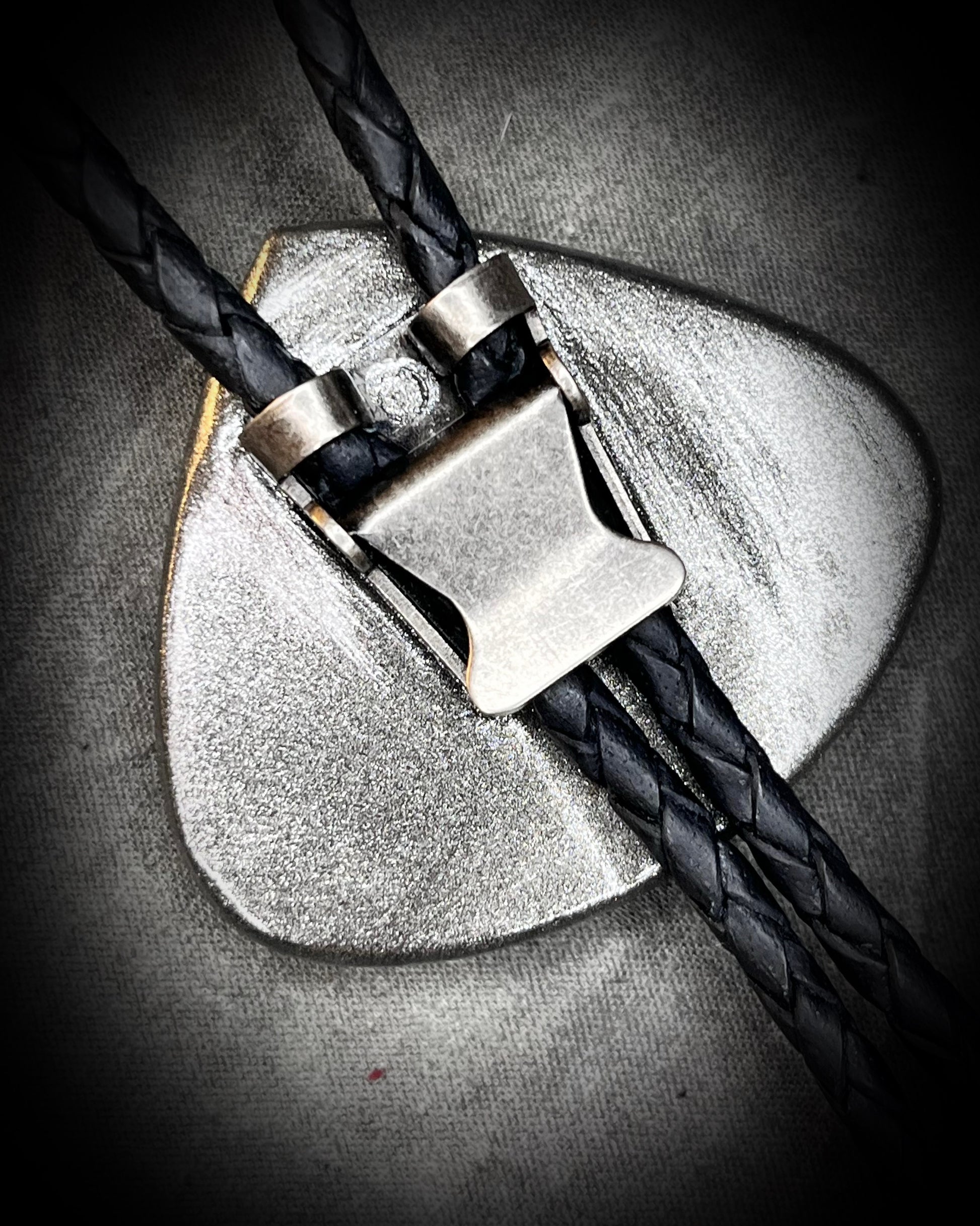 Detail view showing texture of leather cord and silver slide for moonstone bolo tie.