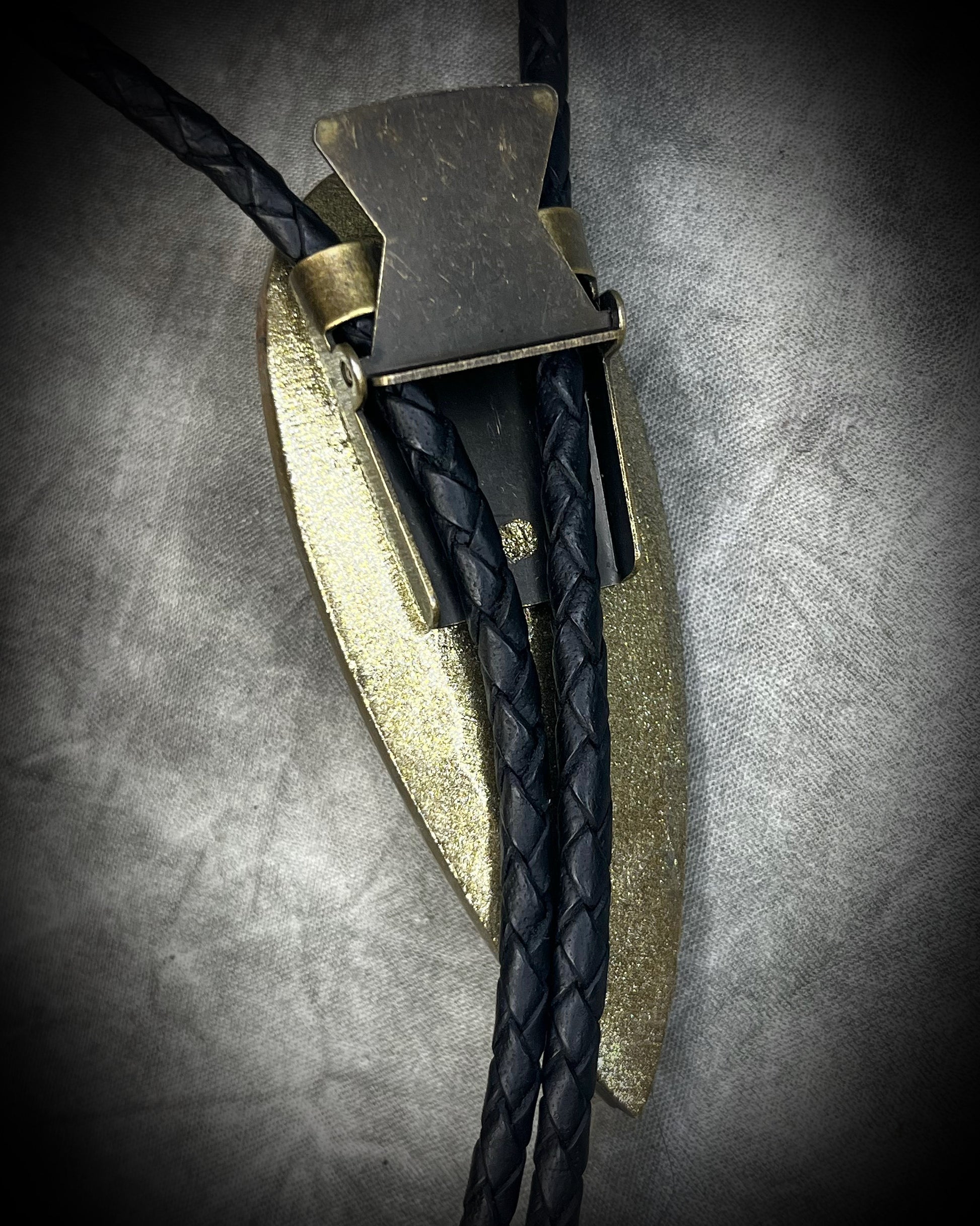 Earthy Orthoceras fossil bolo tie with brown, black and light fossil markings, black leather and black spike tips, handmade by Become Spellbound.