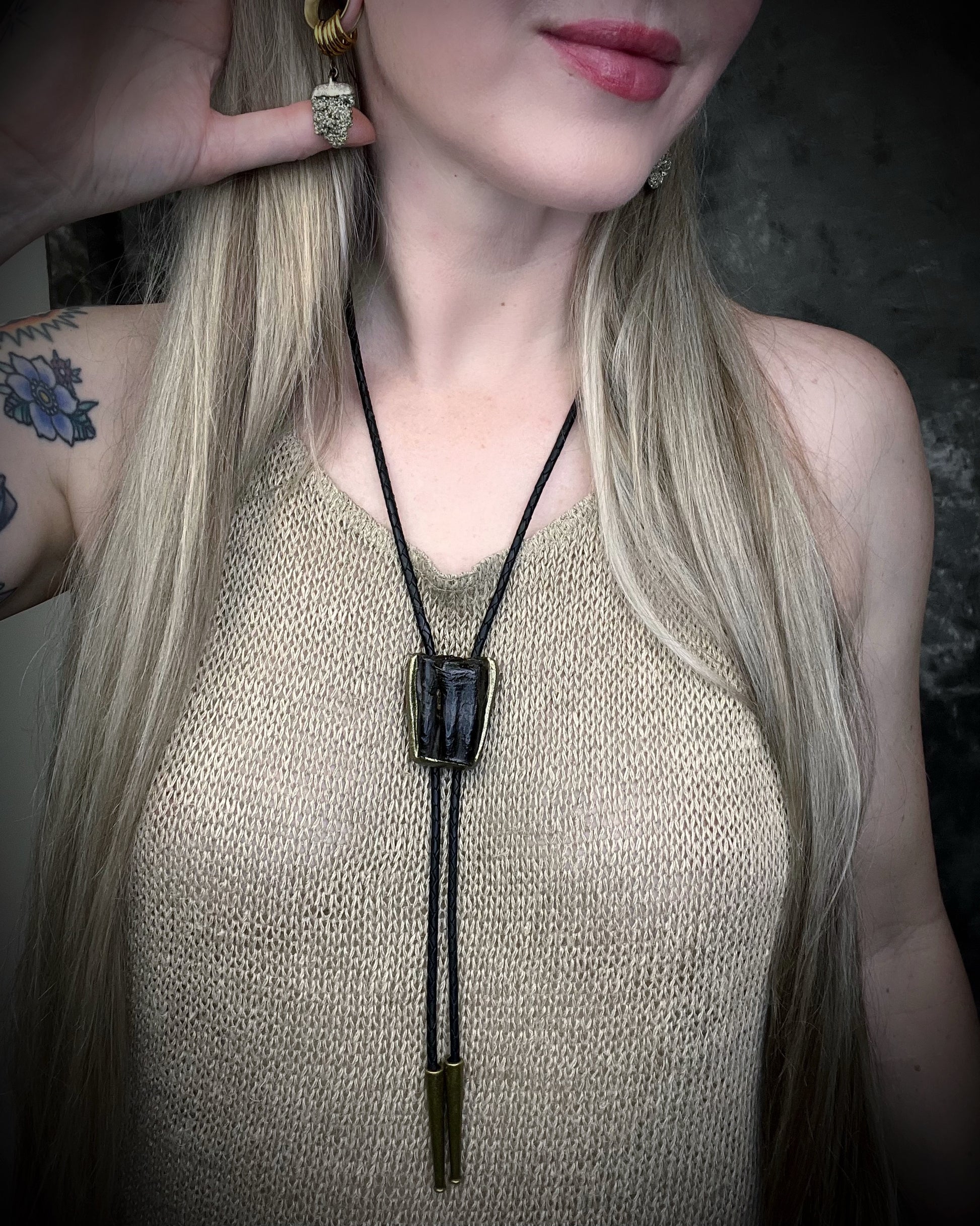 Equus Tooth horse fossil bolo tie for him. Handmade Western inspired bolo jewelry with genuine fossil and gold brass bolo tips on soft black leather. 2026 mens jewelry trends.