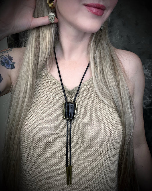 Equus Tooth horse fossil bolo tie for him. Handmade Western inspired bolo jewelry with genuine fossil and gold brass bolo tips on soft black leather. 2026 mens jewelry trends.