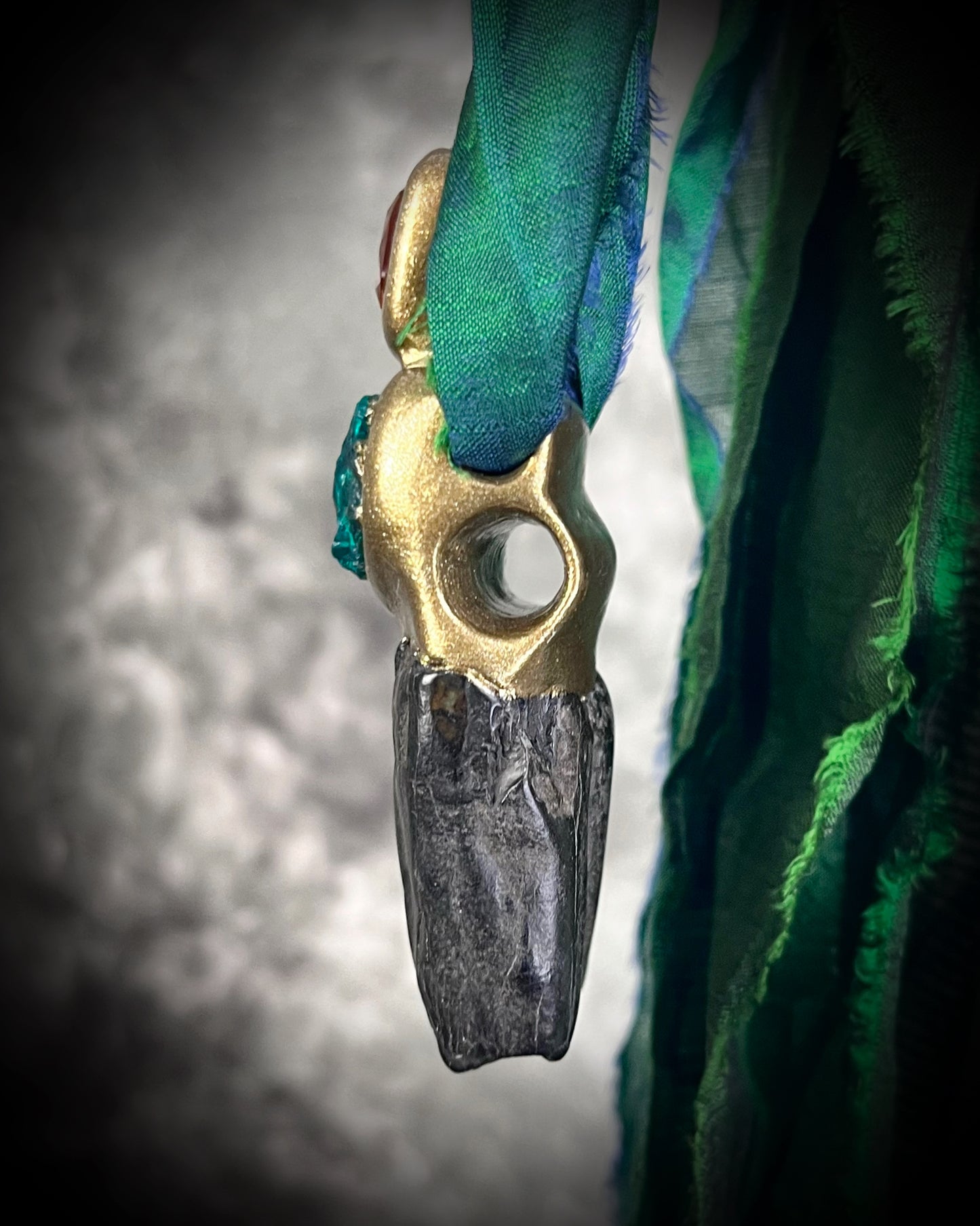 Close-up of gold-tone Equus horse tooth fossil pendant adorned with orange kyanite and green dioptase crystals — mystical handcrafted fossil and crystal necklace.