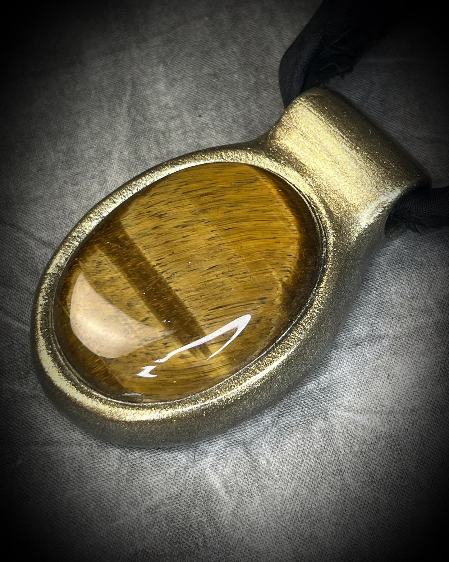 Extra large tiger's eye crystal talisman with golden-brown natural banding, gold finish, and black recycled silk ties, handmade by Become Spellbound in Baltimore, Maryland.