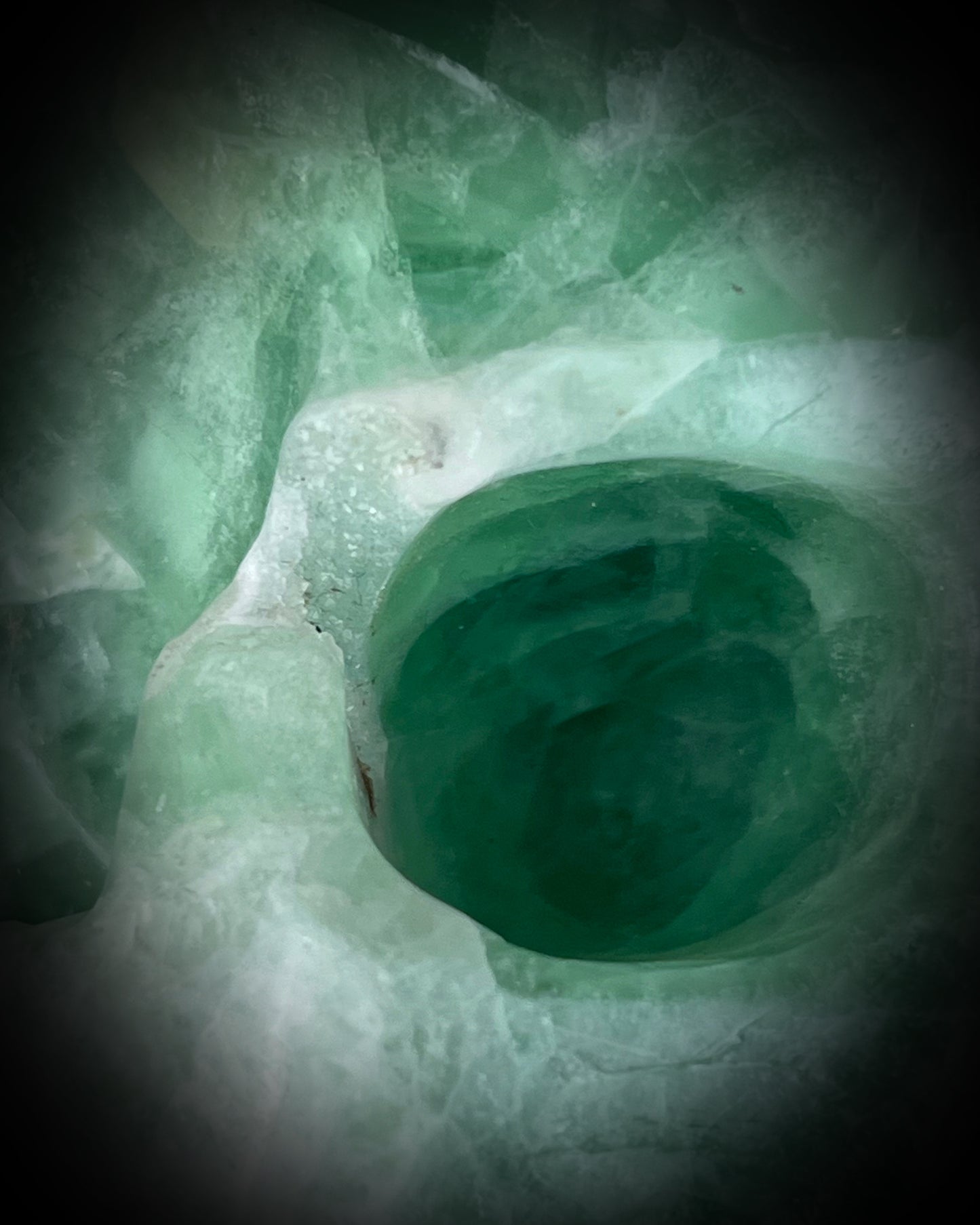 Eye socket druzy crystal pocket on Large 5-inch green fluorite crystal skull with layered green bands and polished carved features.