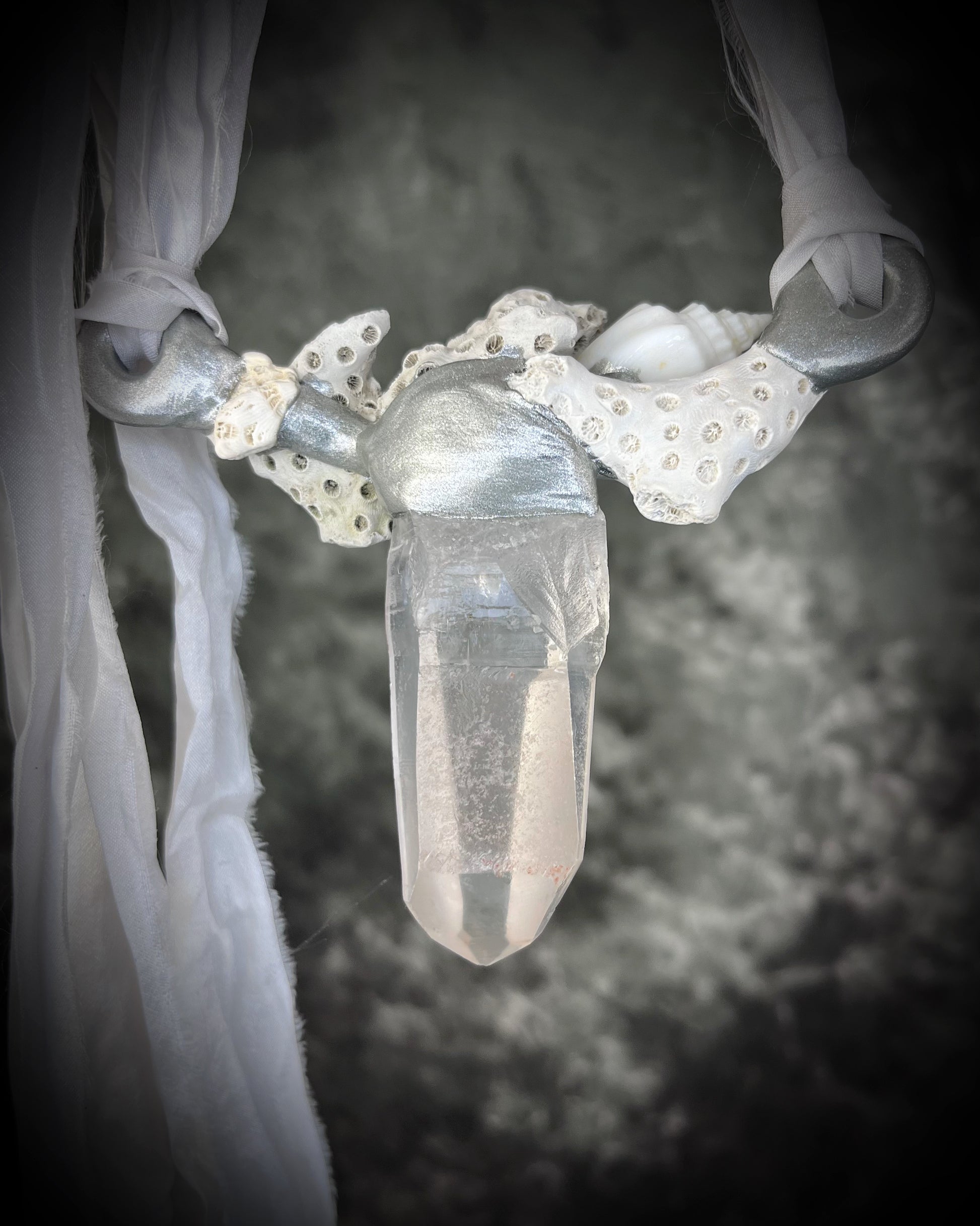 Back view of silver handmade designer bridal or beach bride necklace featuring quartz crystal, white fossilized coral, starfish, seashell and is strung from recycled white silk for an eco-friendly summer beach wedding elegance.  