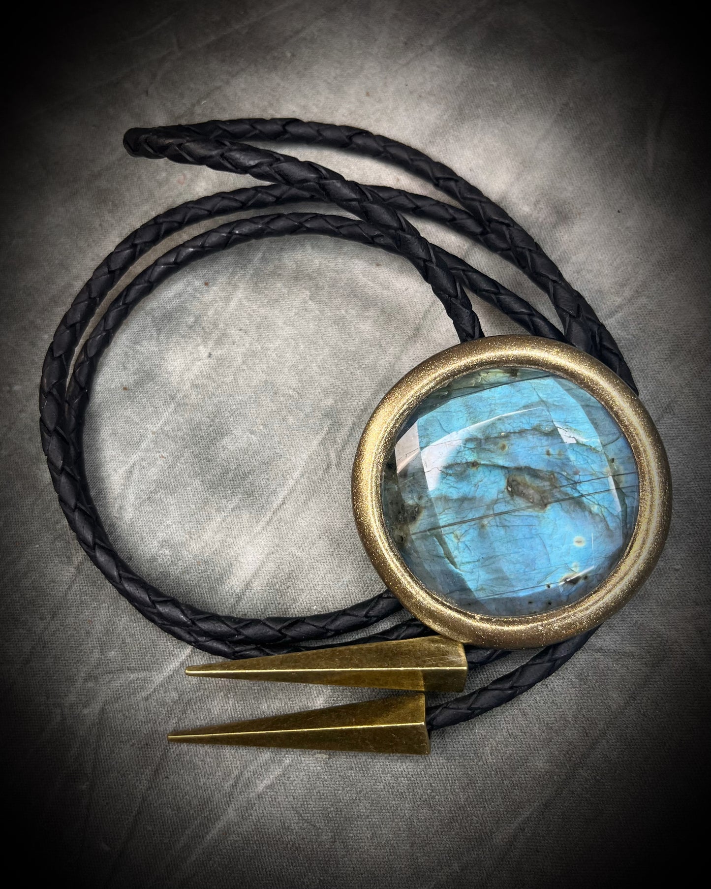 Faceted turquoise blue labradorite bolo tie with black braided leather and gold finish and brass spike tips. Statement Bolo Tie with Labradorite, Western and Witchy Bolo Tie Talisman.