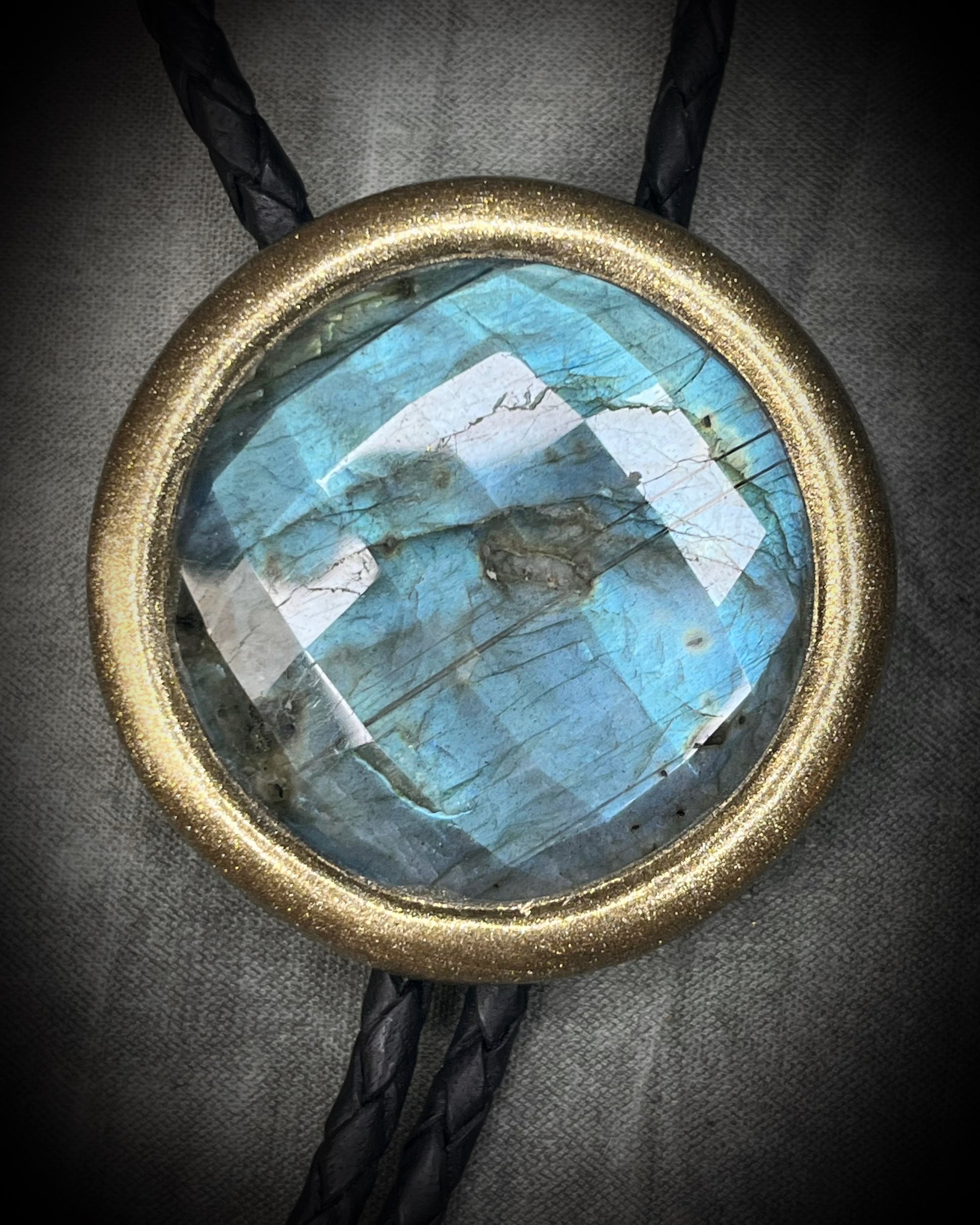 Faceted turquoise blue labradorite bolo tie with black braided leather and gold finish and brass spike tips. Statement Bolo Tie with Labradorite, Western and Witchy Bolo Tie Talisman.