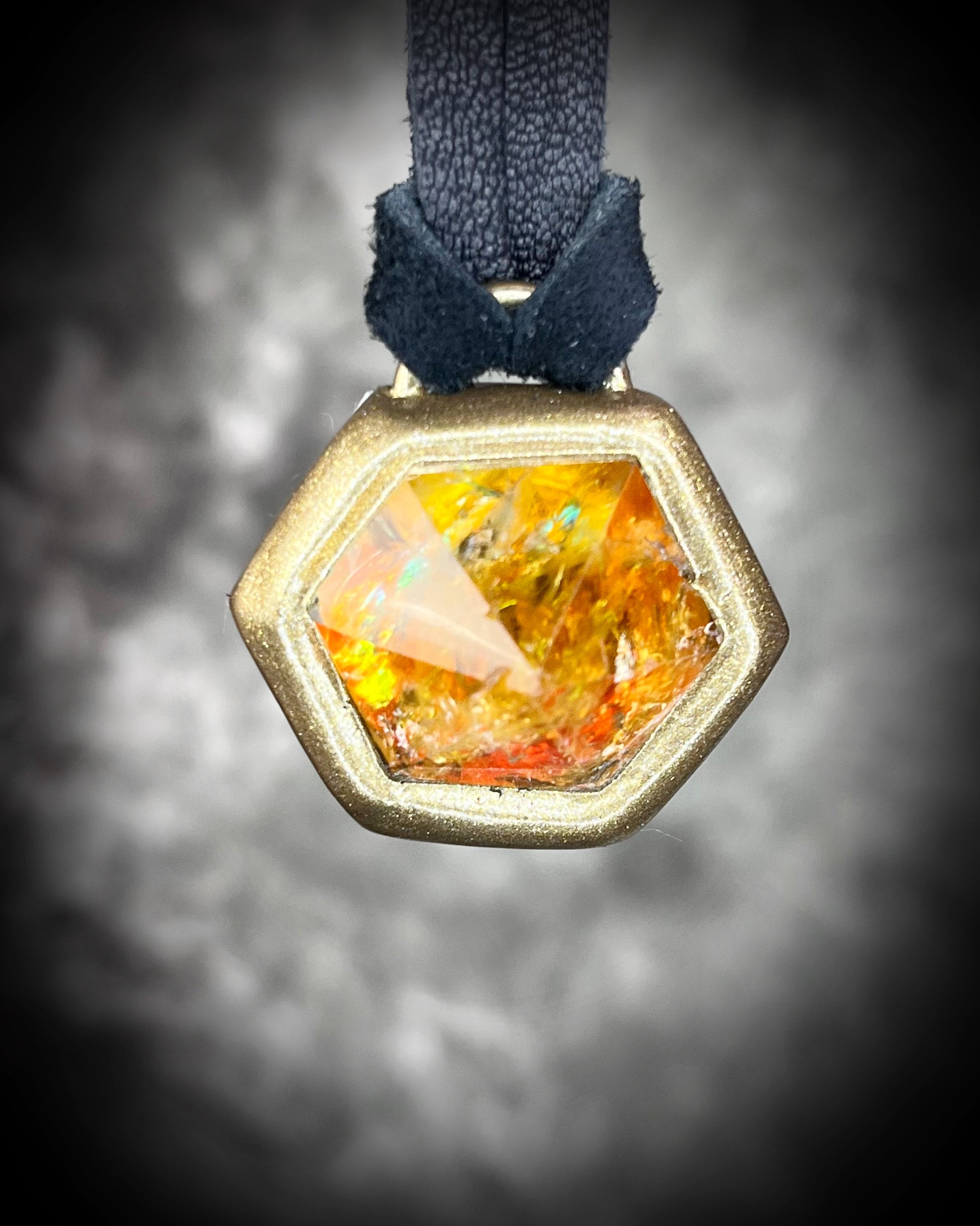 Fiery citrine hexagon crystal pendant with red, green, and orange opalescent flash in black finish on black leather cord — handcrafted statement talisman